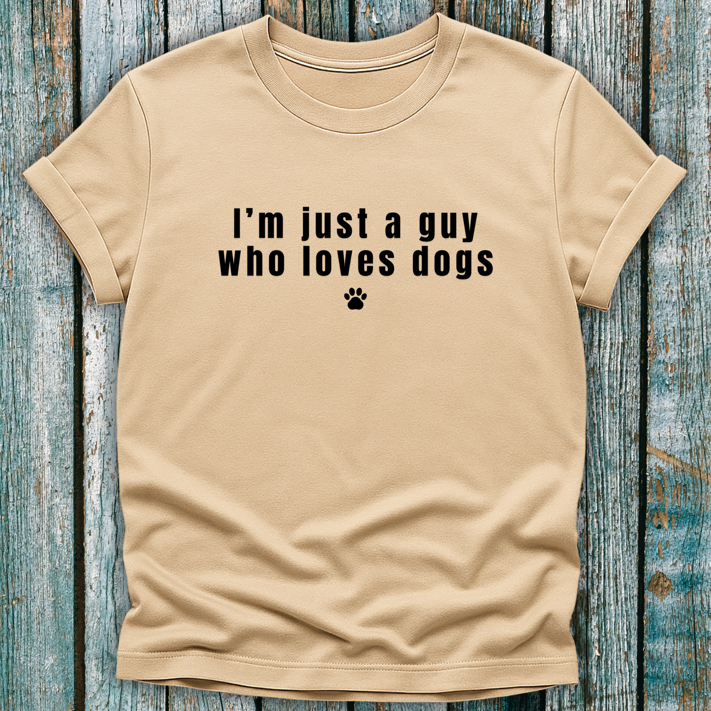 Beige t-shirt with 'I'm just a guy who loves dogs' text on a wooden surface