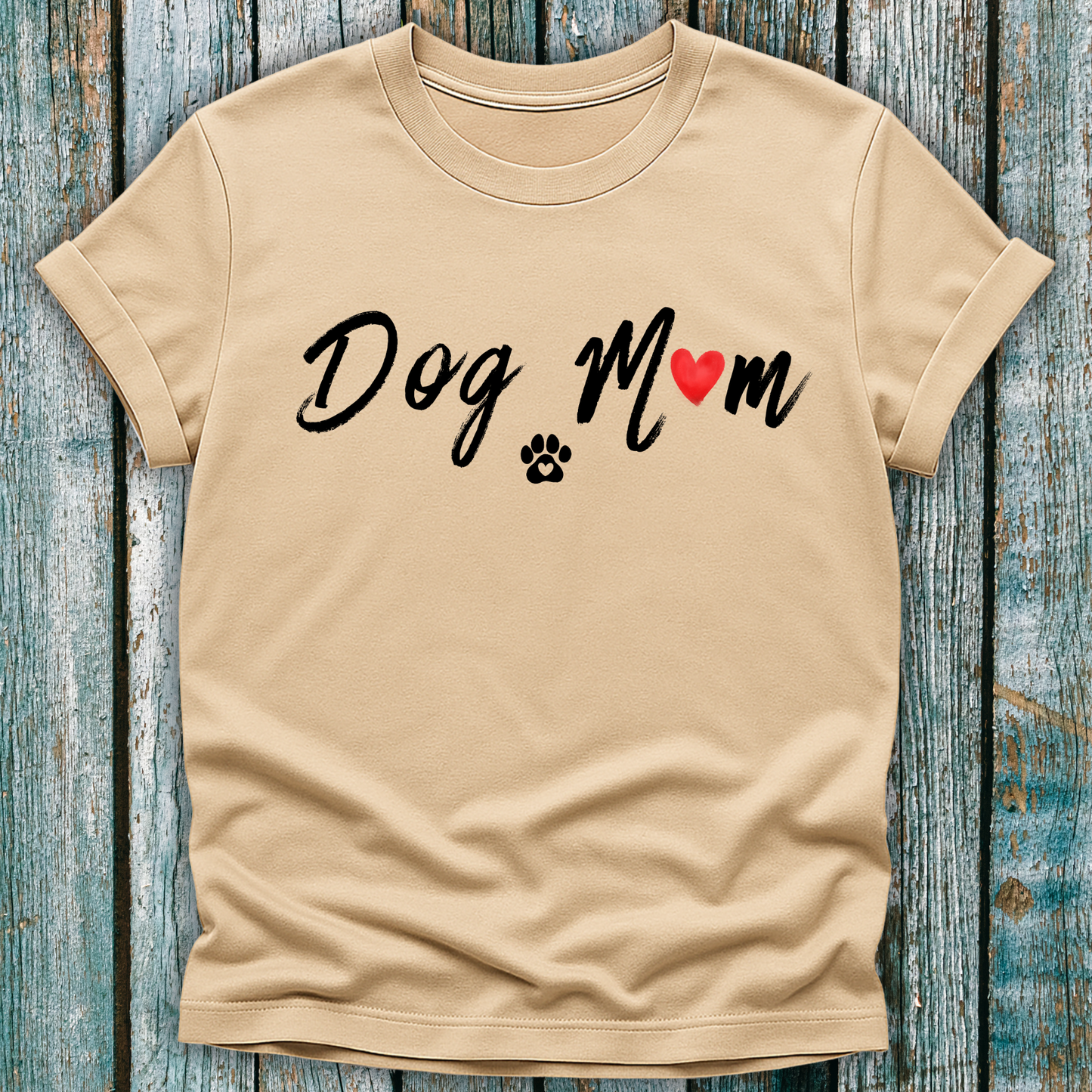 Beige t-shirt with 'Dog Mom' 'Dog Mum' text and heart and paw graphic on a wooden surface