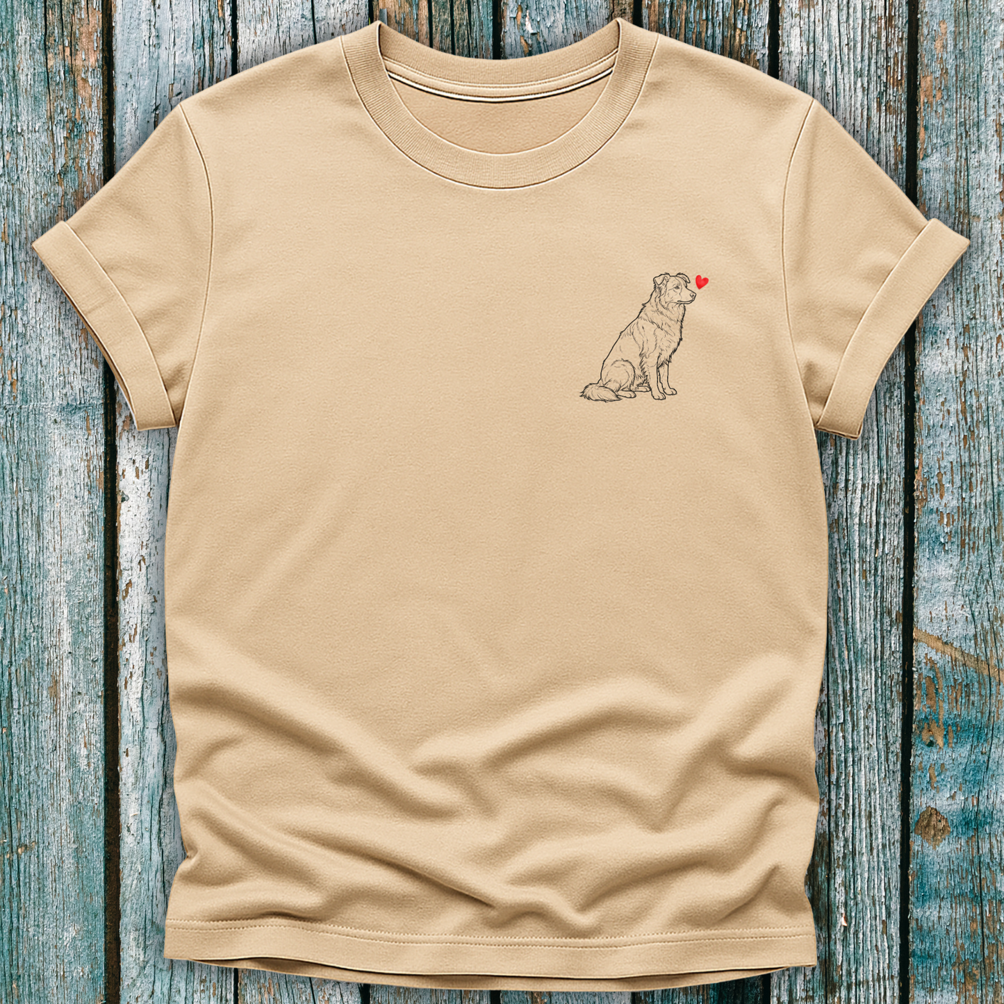 Beige t-shirt with a Greyhound dog graphic and a red heart on a wooden surface