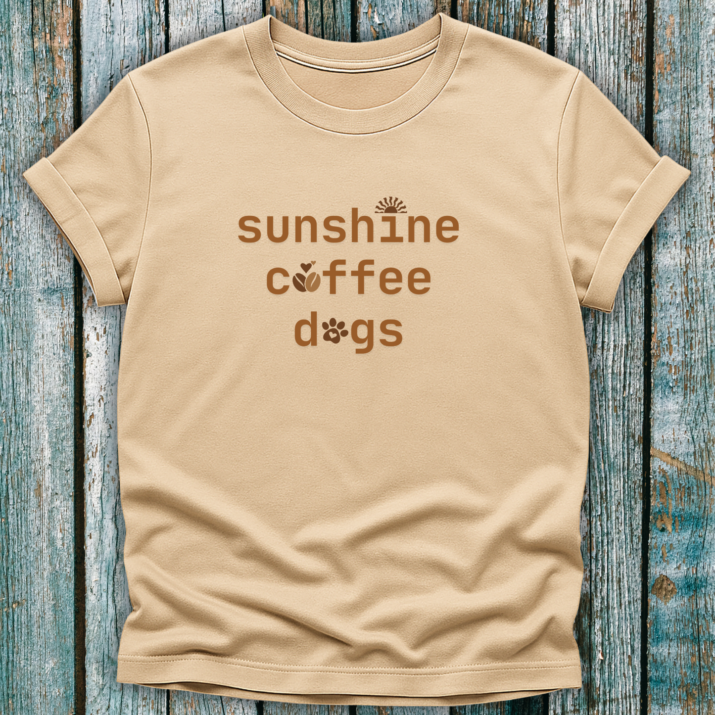 Beige t-shirt with 'sunshine coffee dogs' text on a wooden surface