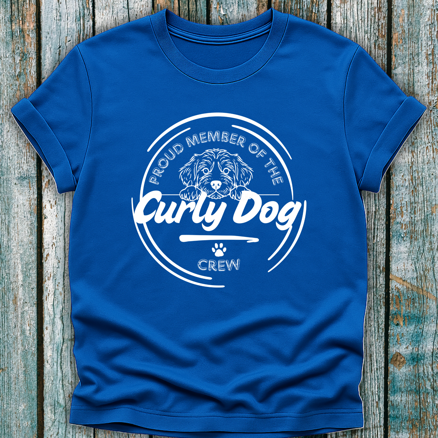 Blue t-shirt with 'Proud Member of the Curly Dog Crew' text and graphic on a wooden surface