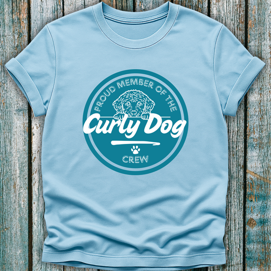 Light blue t-shirt with 'Proud Member of the Curly Dog Crew' design on a wooden surface