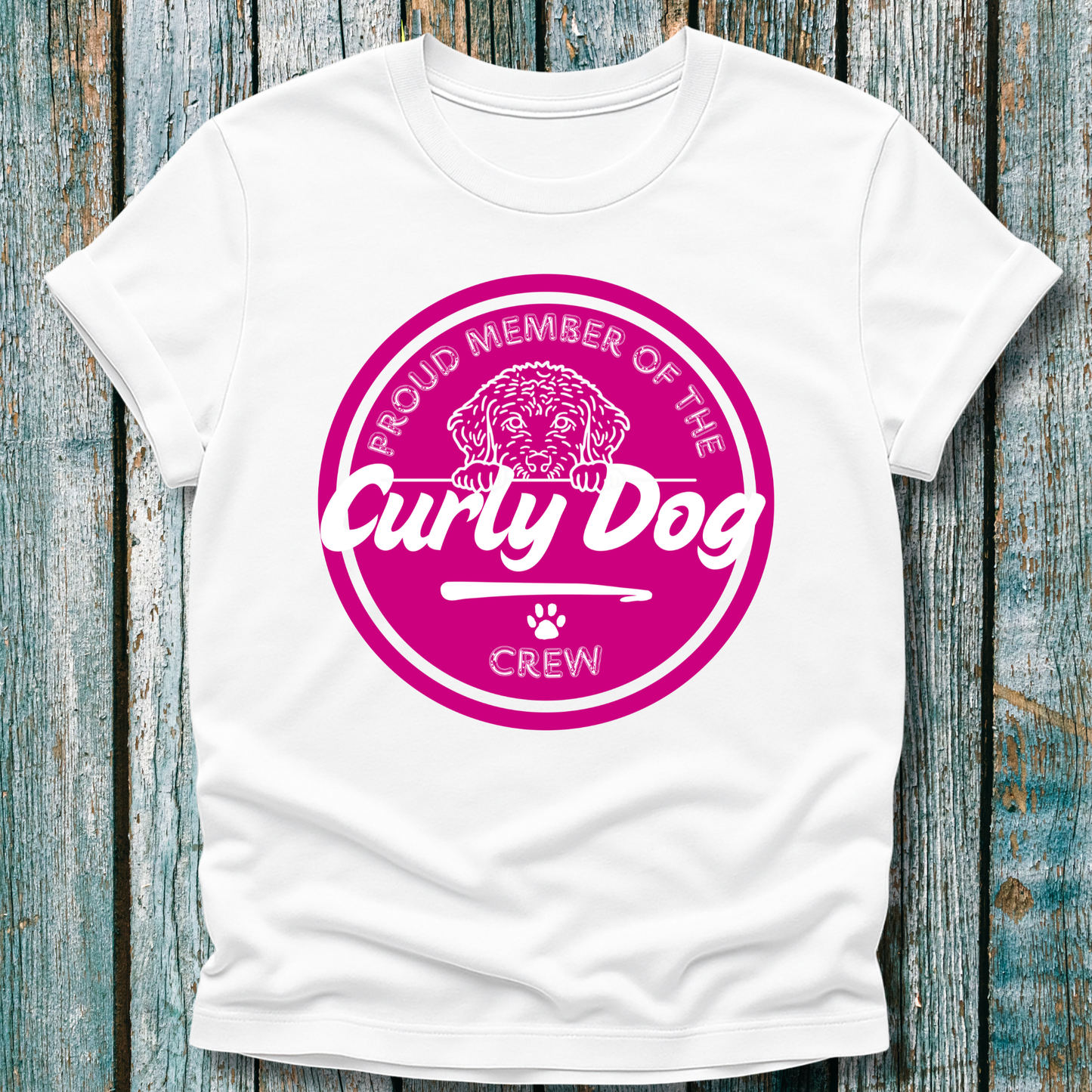 White t-shirt with pink 'Curly Dog' logo on a wooden background