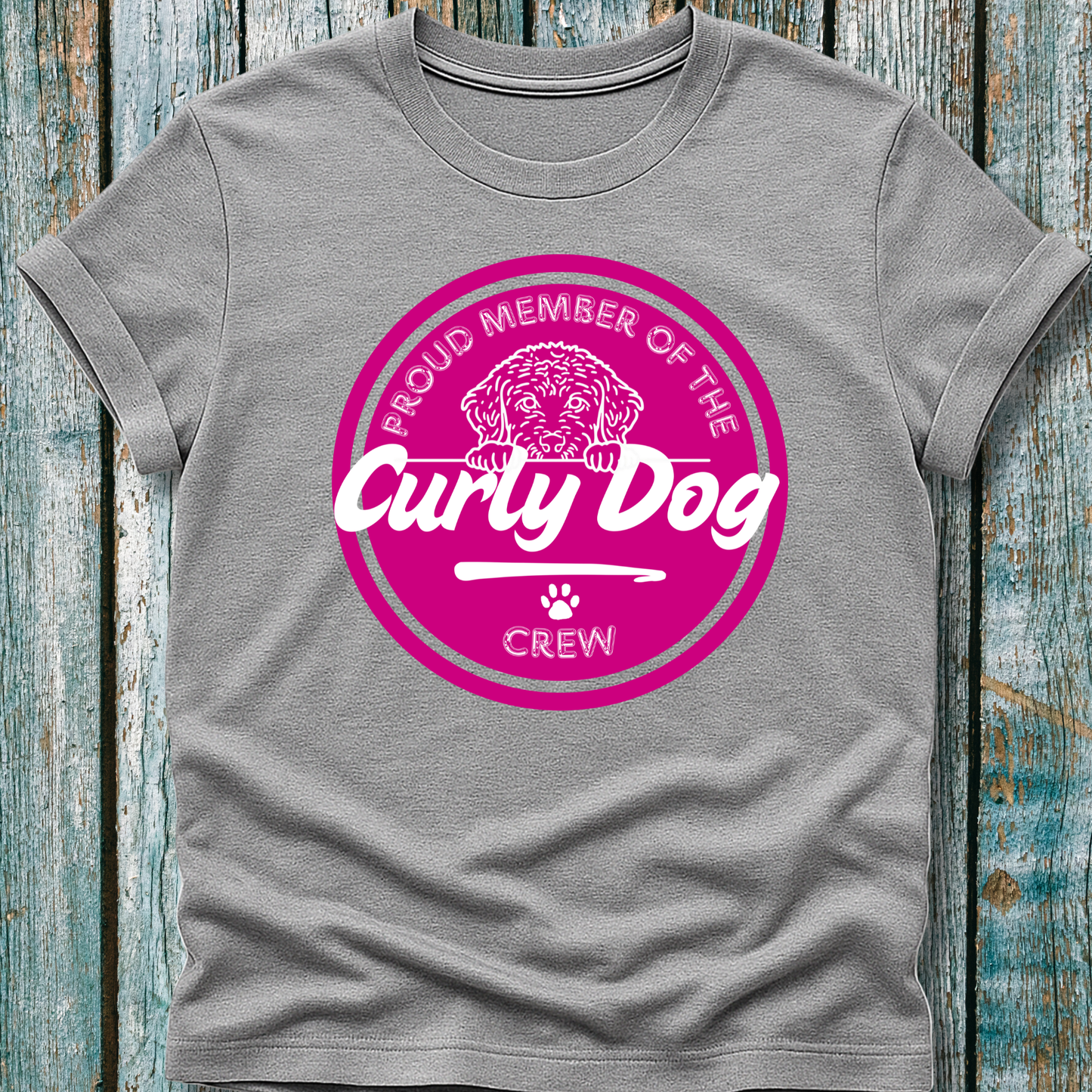 Gray t-shirt with pink 'Proud Member of the Curly Dog Crew' graphic on a wooden surface