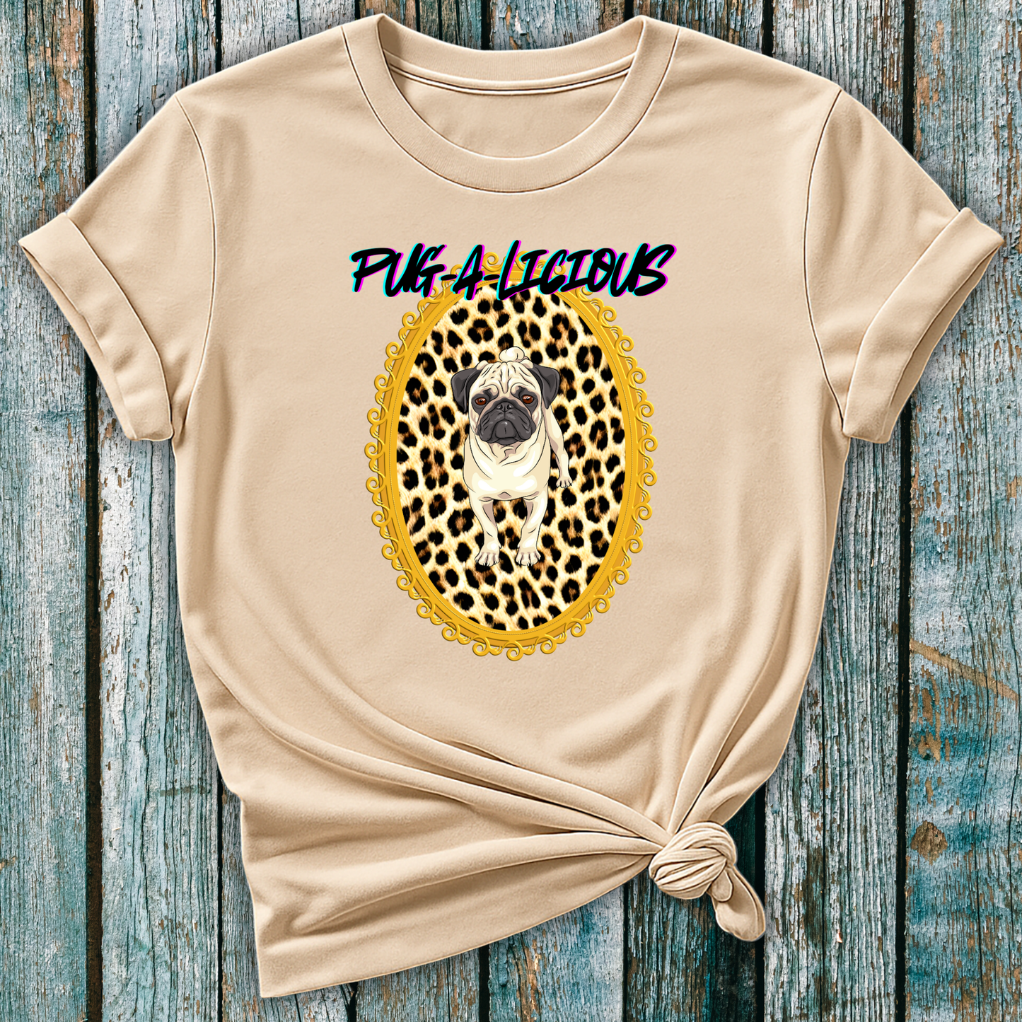 Beige t-shirt with a pug graphic nand text saying pug-a-licious on a wooden surface