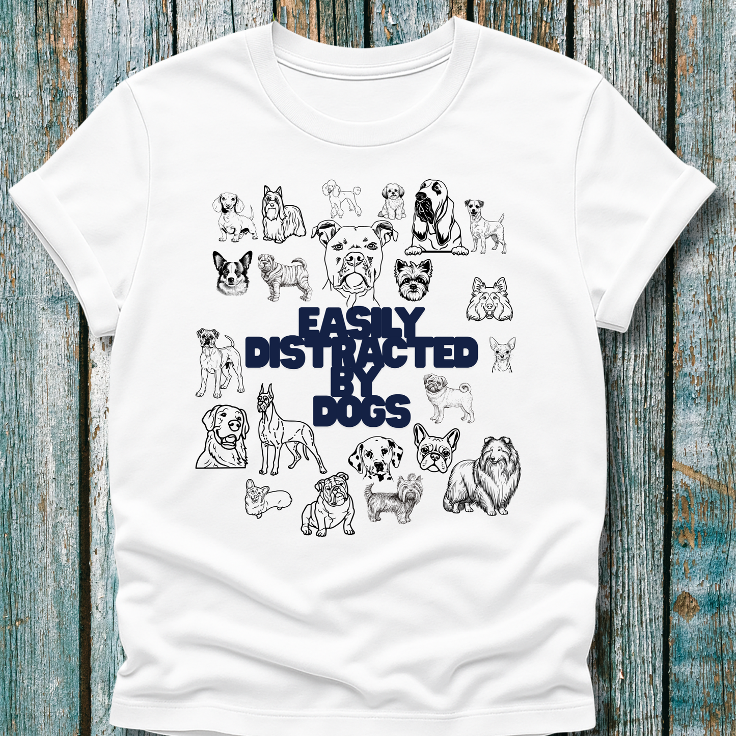 White t-shirt with black and blue dog illustrations and 'Easily Distracted by Dogs' text on a wooden surface.