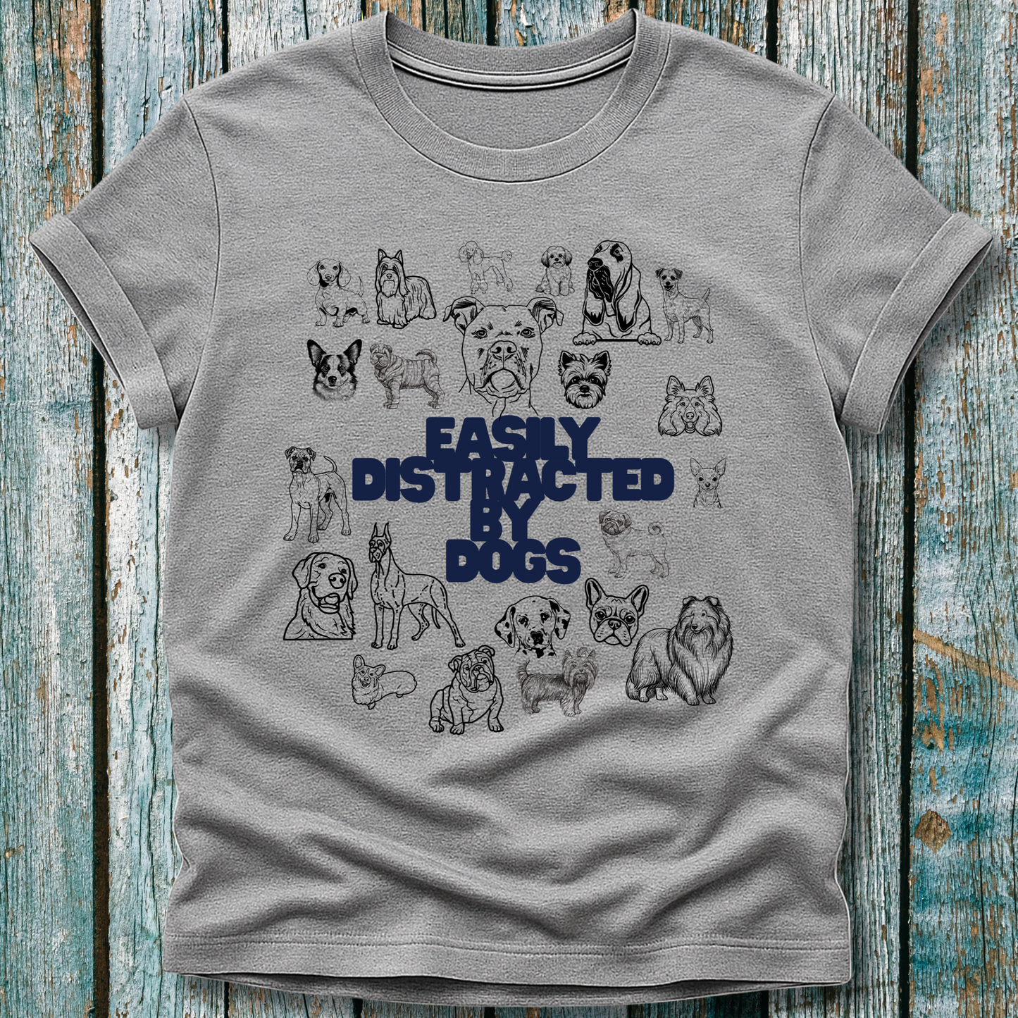 Gray t-shirt with dog illustrations and 'Easily Distracted by Dogs' text on a wooden background