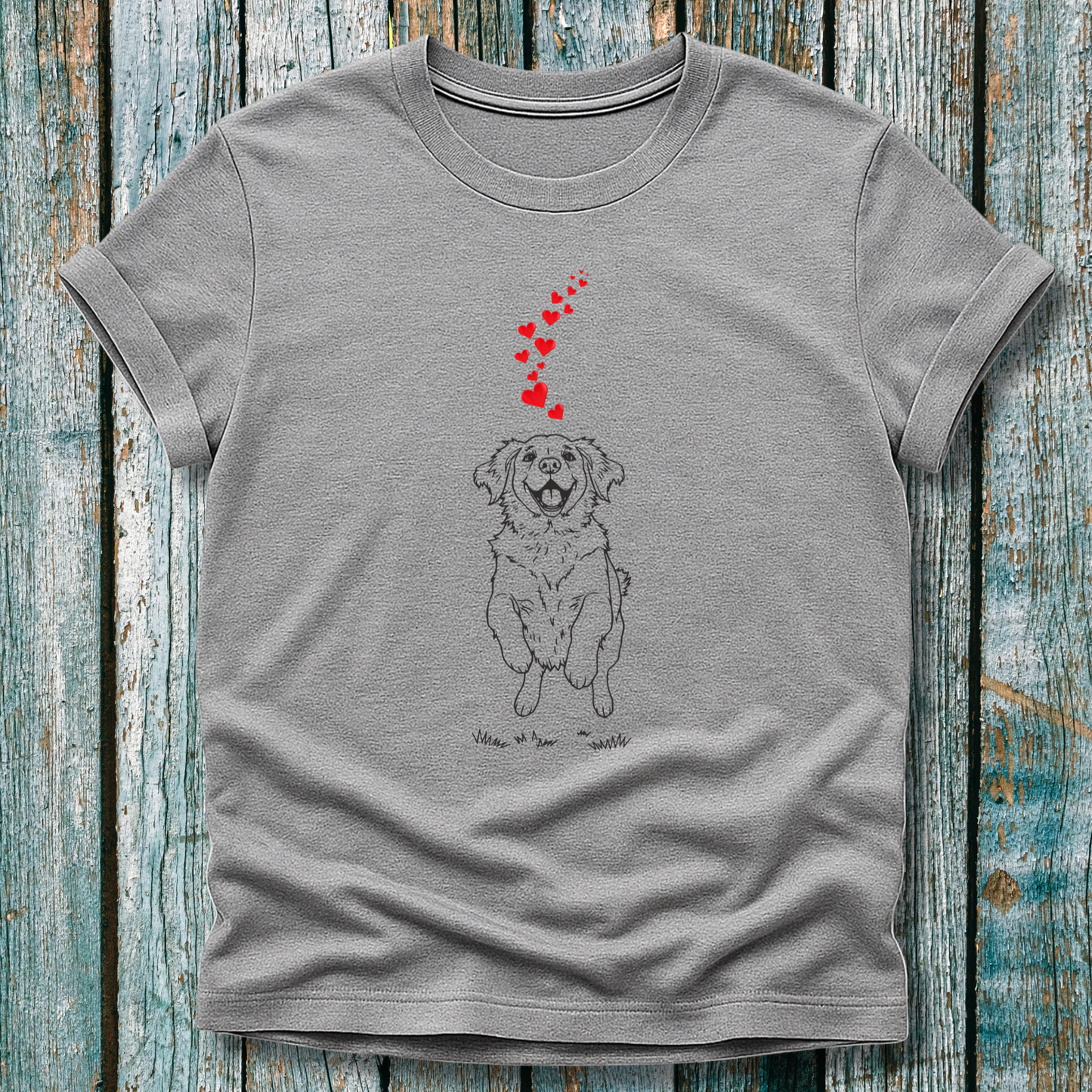 Gray t-shirt with a dog illustration and heart shapes on a wooden surface