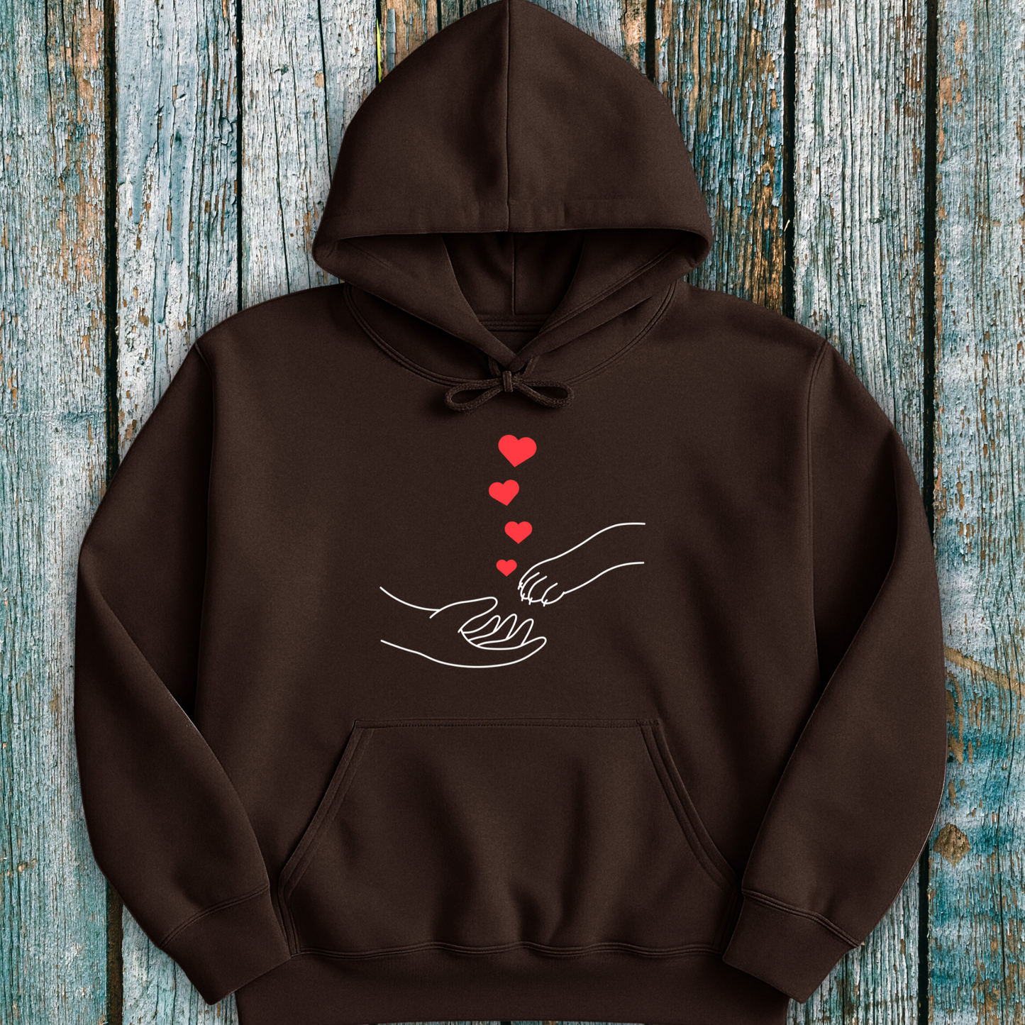  Brown hoodie with a design of hands holding paws and hearts on a wooden surface