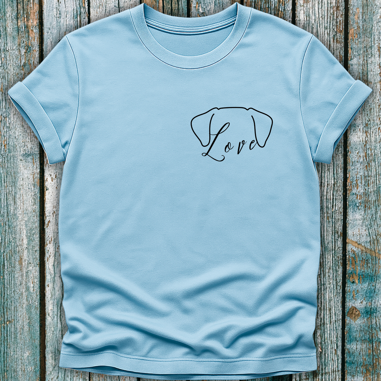 Light blue t-shirt with a dog ears graphic and 'Love' text on a wooden surface