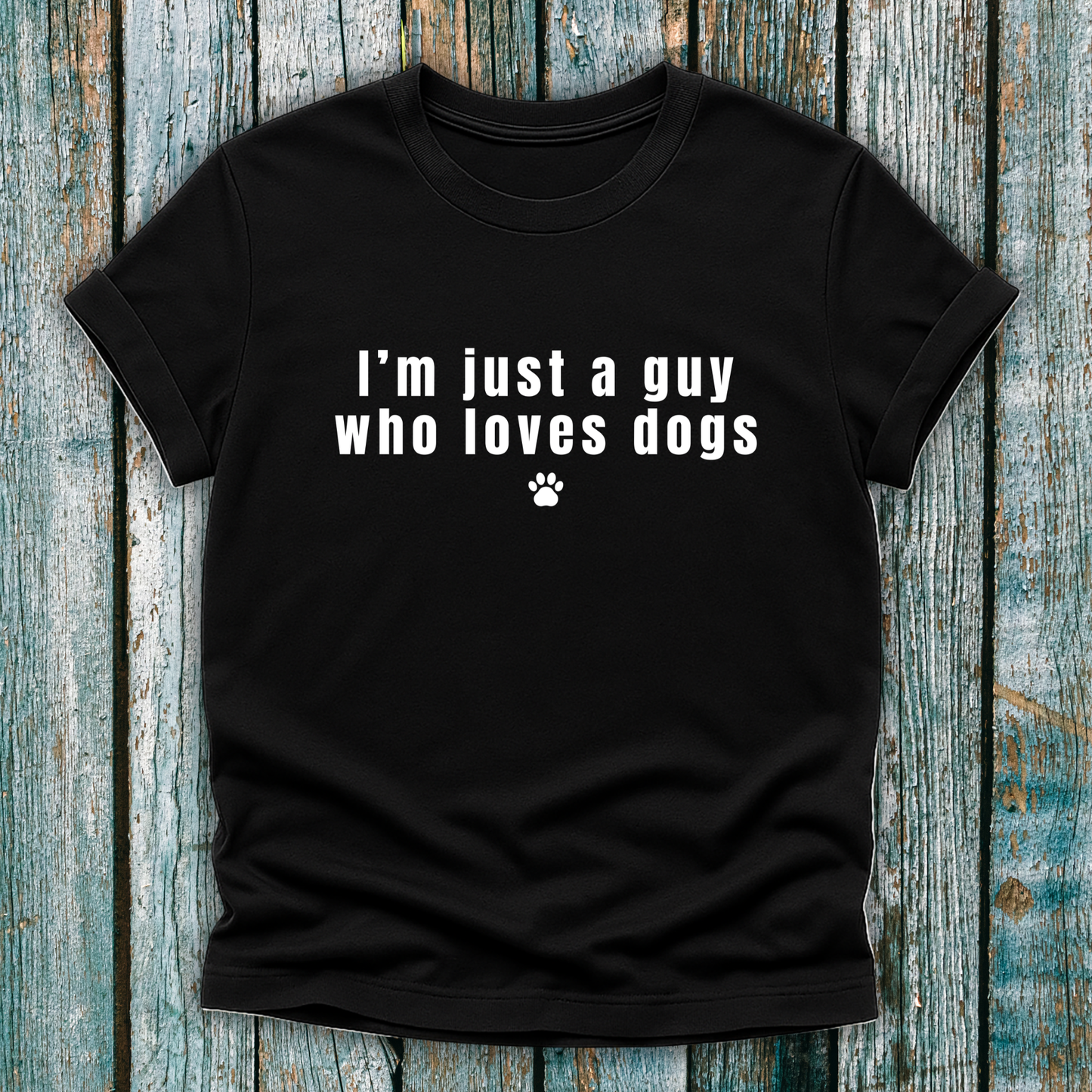 Black t-shirt with 'I'm just a guy who loves dogs' text on a wooden surface