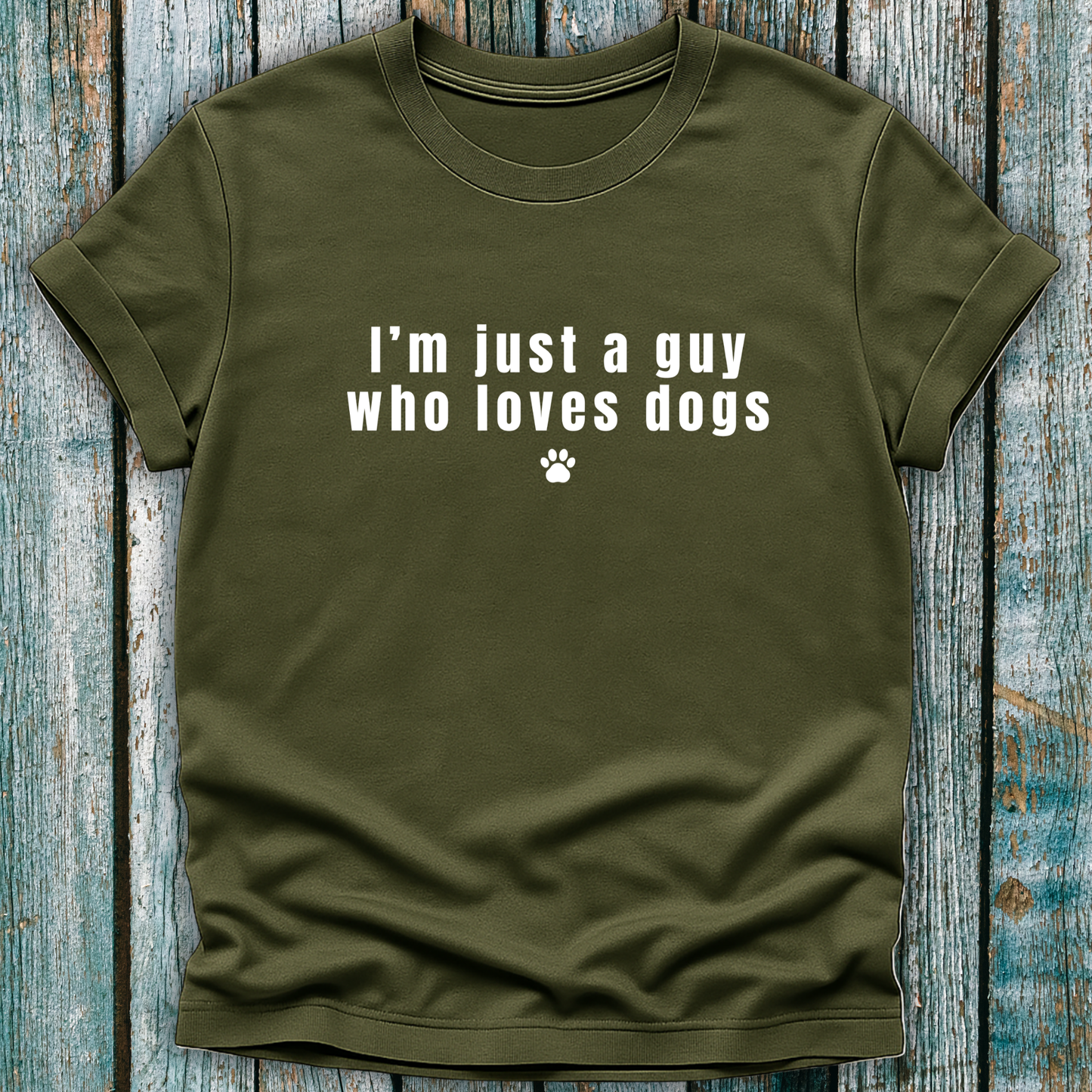 Green t-shirt with 'I'm just a guy who loves dogs' text on a wooden surface