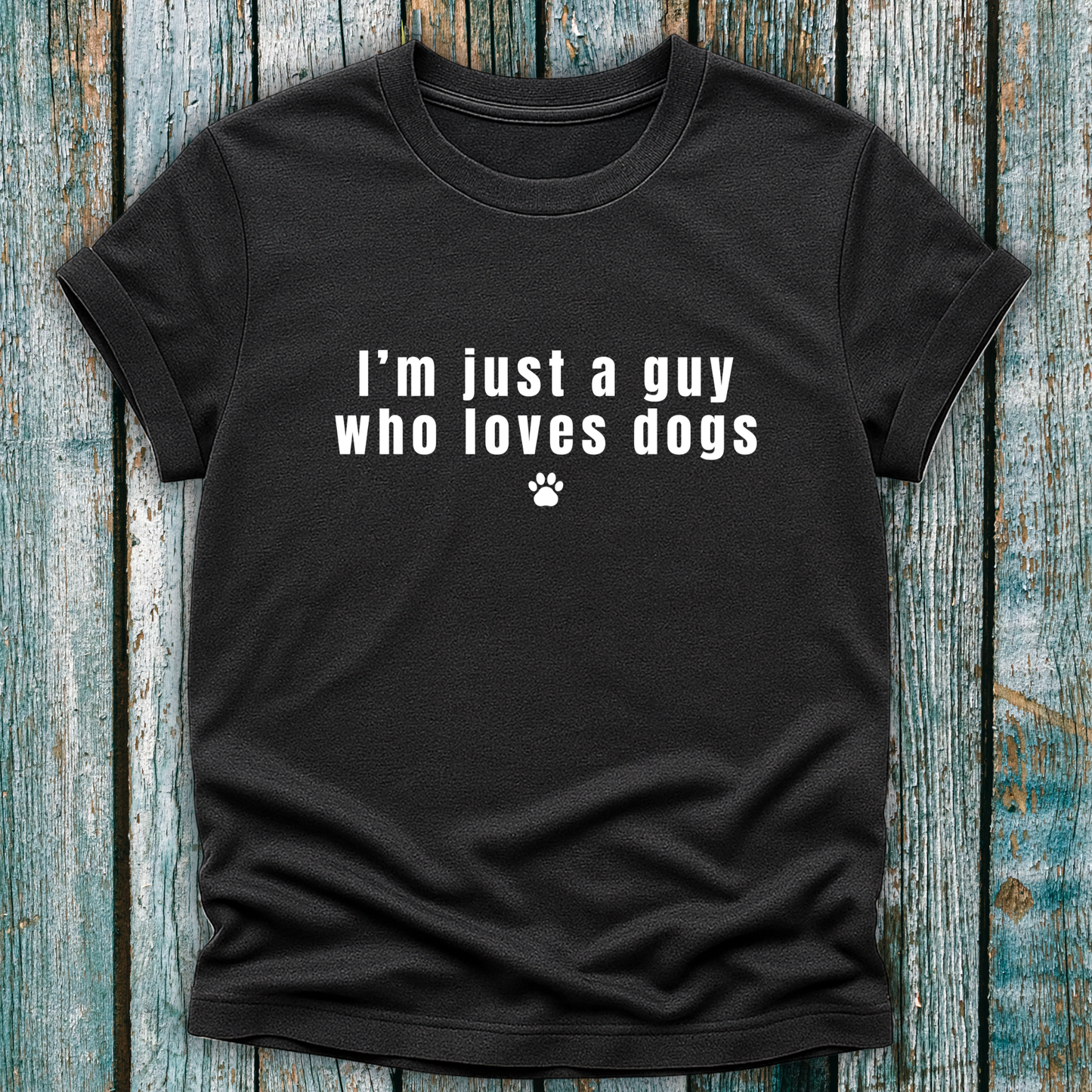 Black t-shirt with 'I'm just a guy who loves dogs' text on a wooden surface