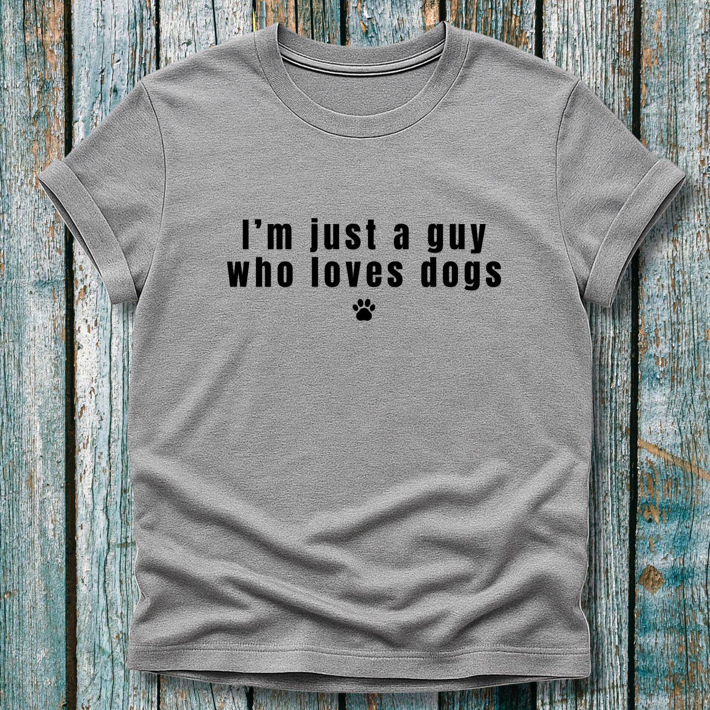 Gray t-shirt with 'I'm just a guy who loves dogs' text on a wooden surface