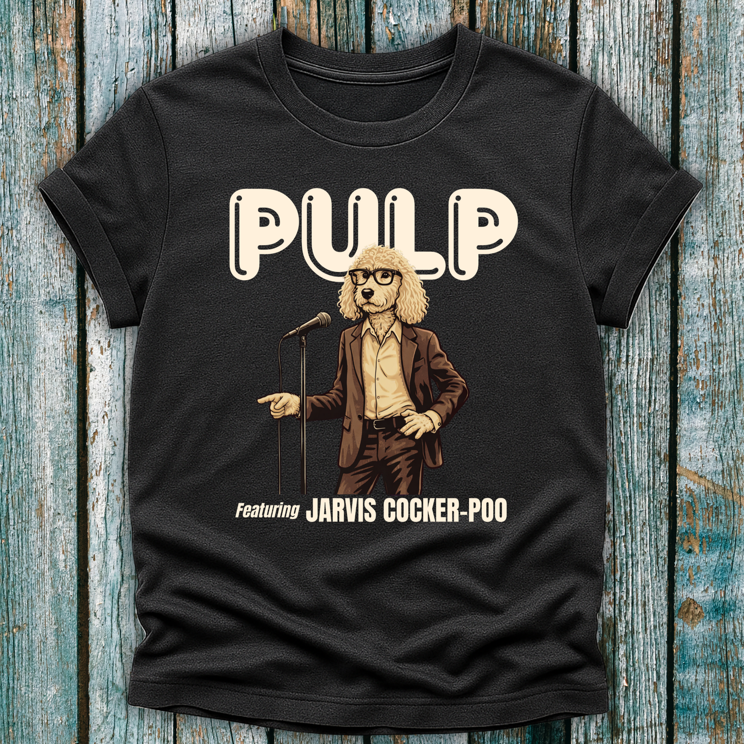 Black t-shirt with a graphic of a dog in a suit and glasses holding a microphone, labeled 'Pulp Featuring Jarvis Cocker Poo' on a wooden surface.