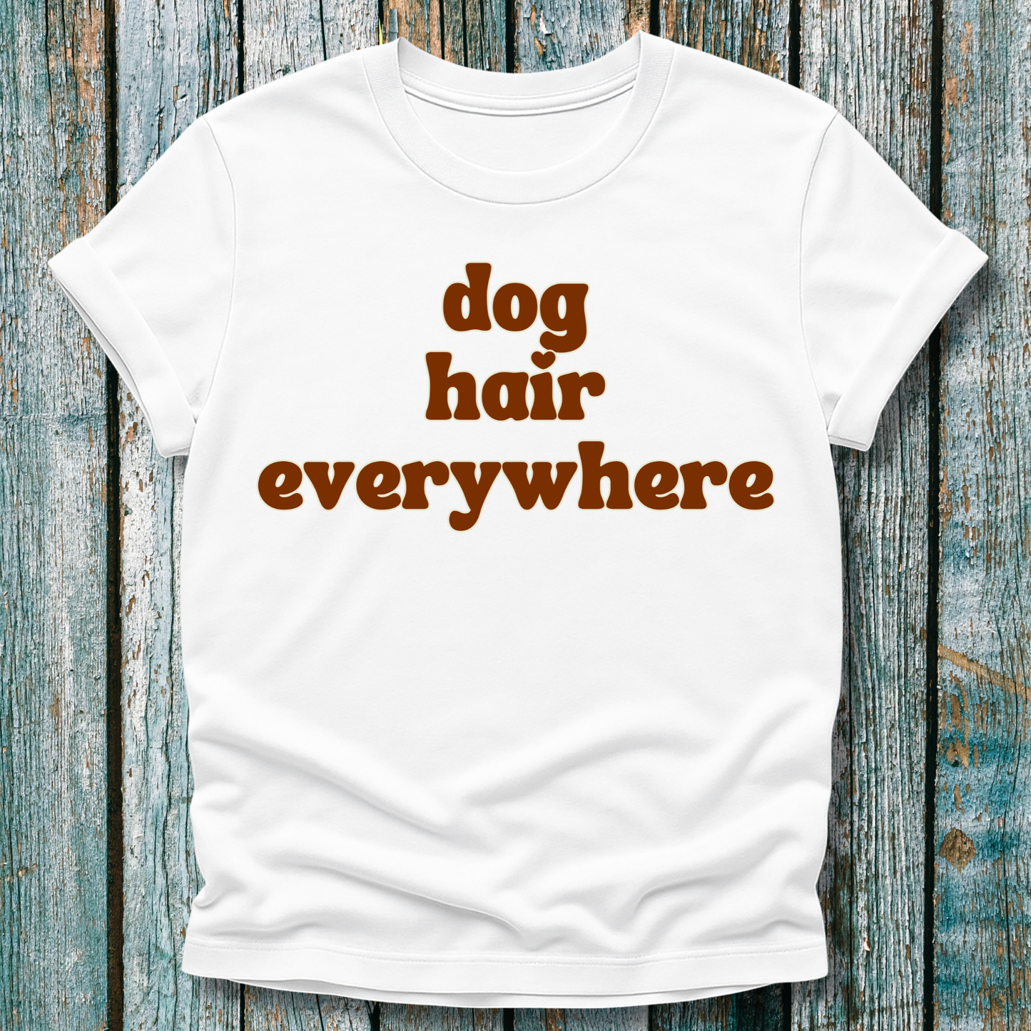 White t-shirt with 'dog hair everywhere' text on a wooden background