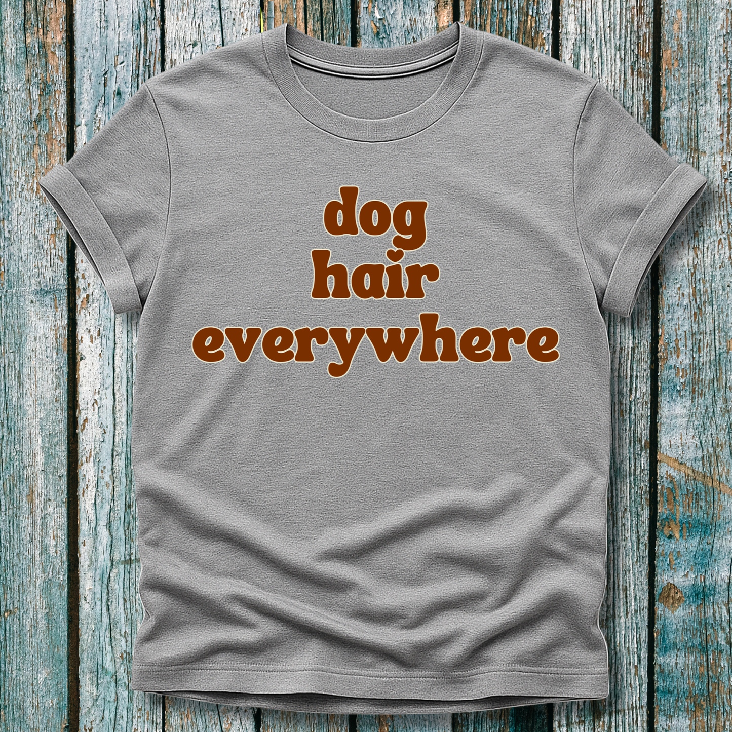 Gray t-shirt with 'dog hair everywhere' text on a wooden surface