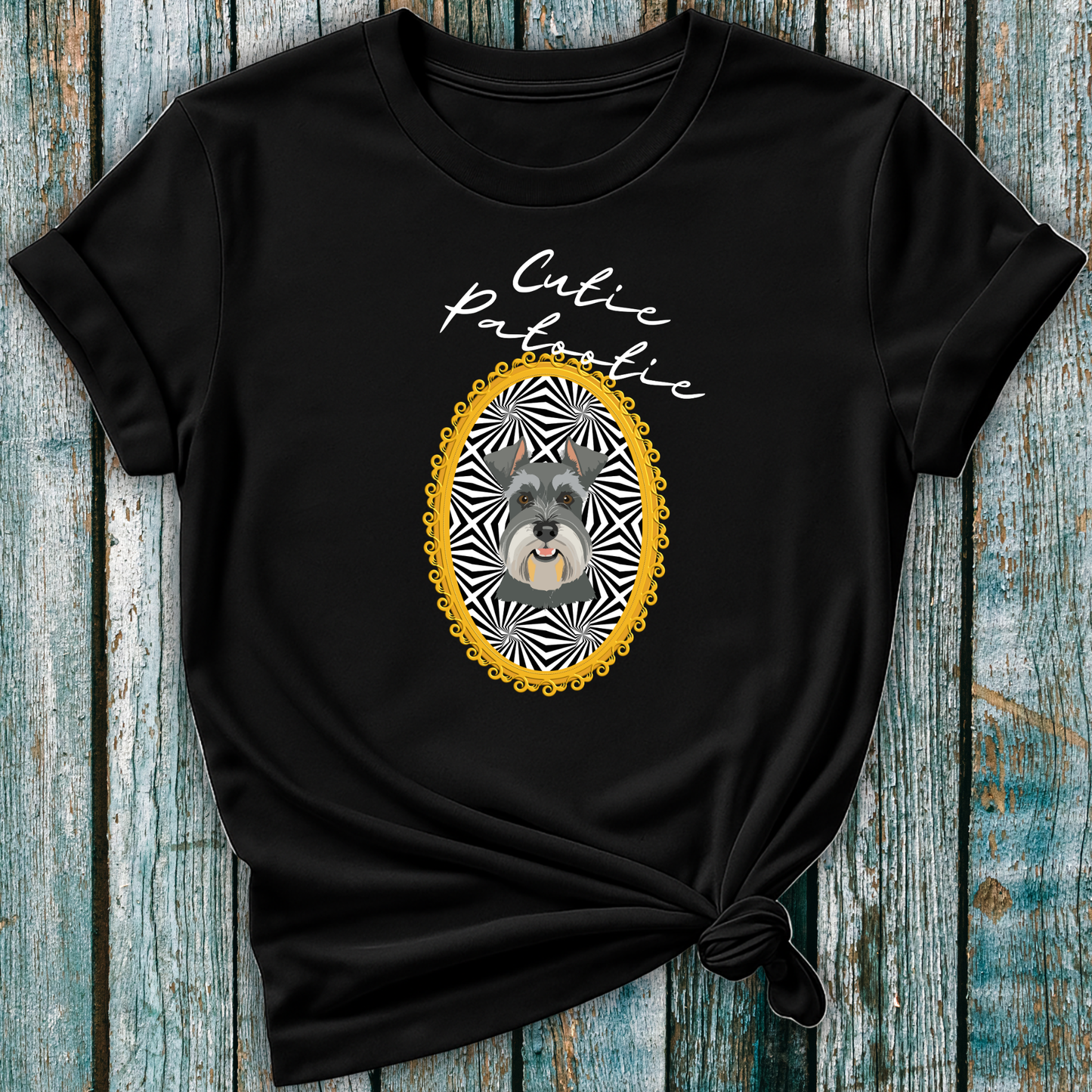 Black t-shirt with a Schnauzer illustration and 'Cutie Patootie' text on a wooden surface