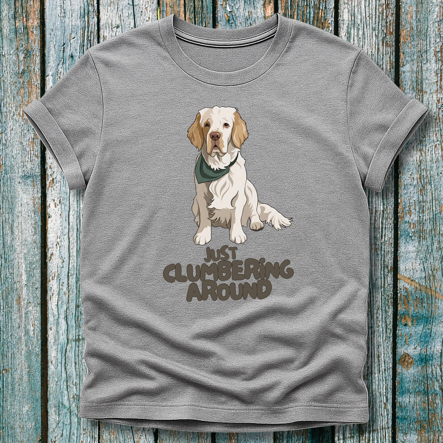 Gray t-shirt with a Clumber Spaniel graphic and text 'Just Clumbering Around' on a wooden surface
