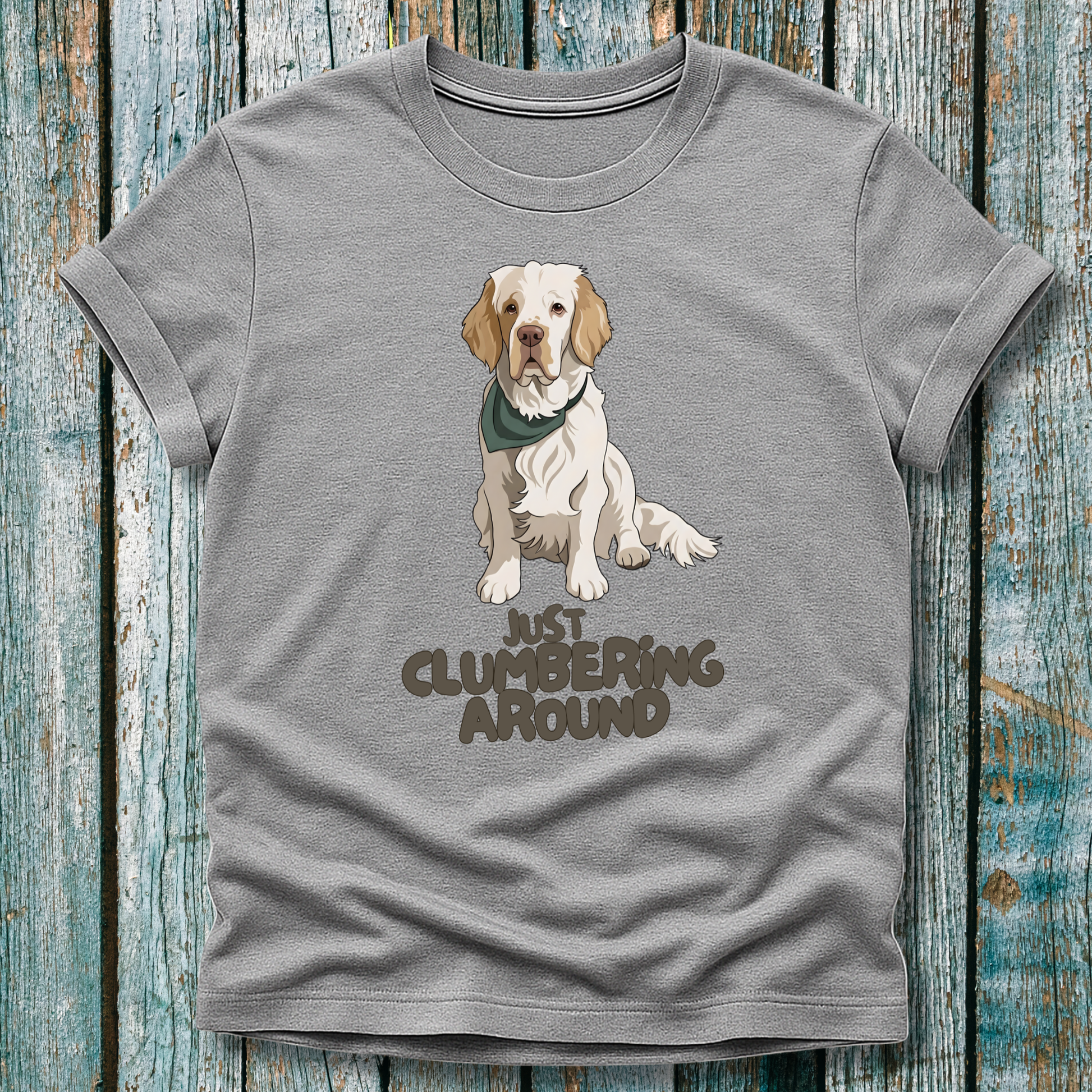 Gray t-shirt with a Clumber Spaniel graphic and text 'Just Clumbering Around' on a wooden surface