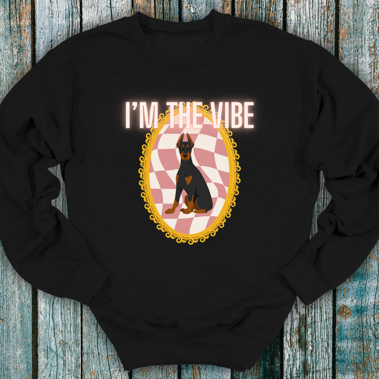 Black sweatshirt with a graphic of a Doberman dog and 'I'm the Vibe' text on a wooden surface