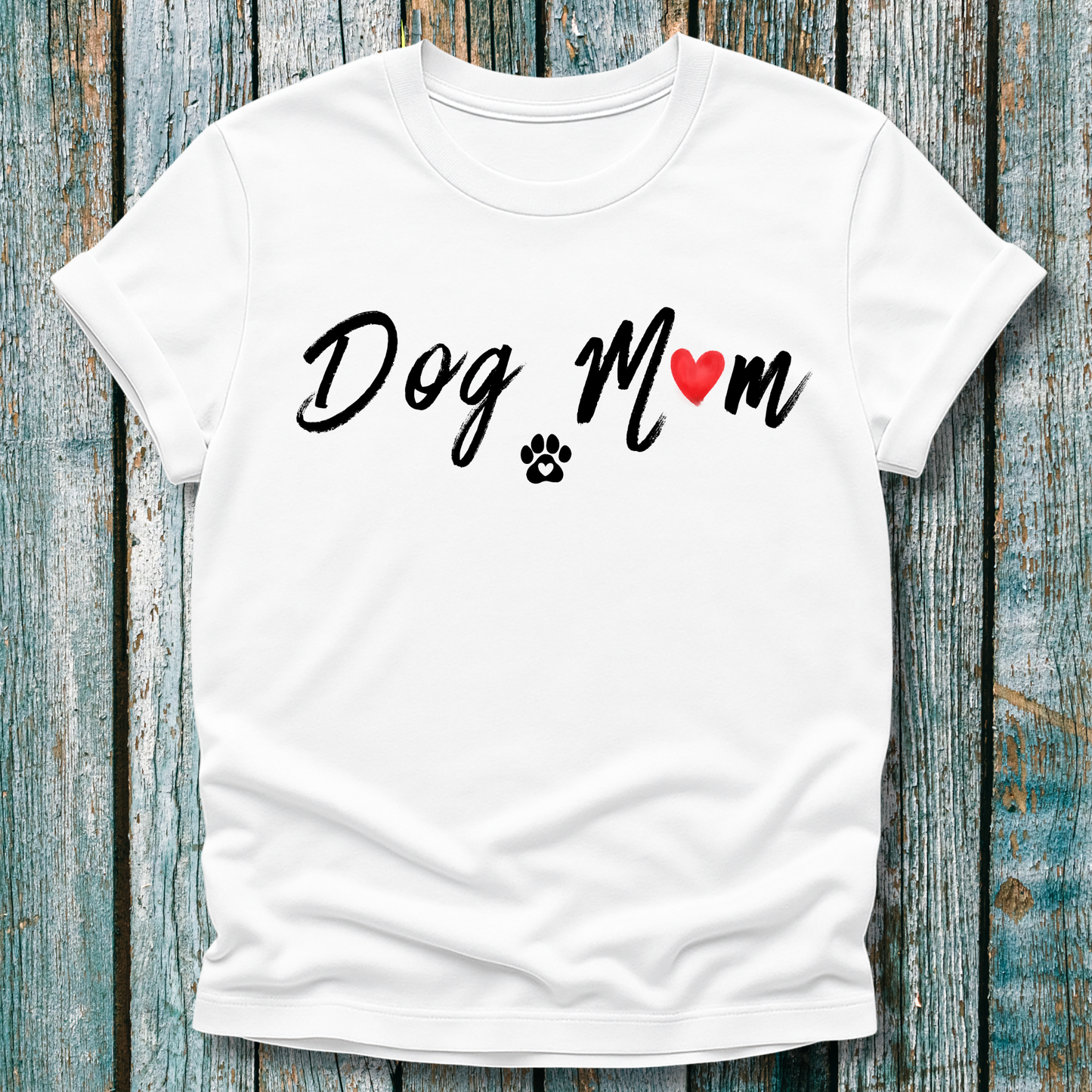 White t-shirt with 'Dog Mom' 'Dog Mum' text and heart and paw graphic on a wooden surface