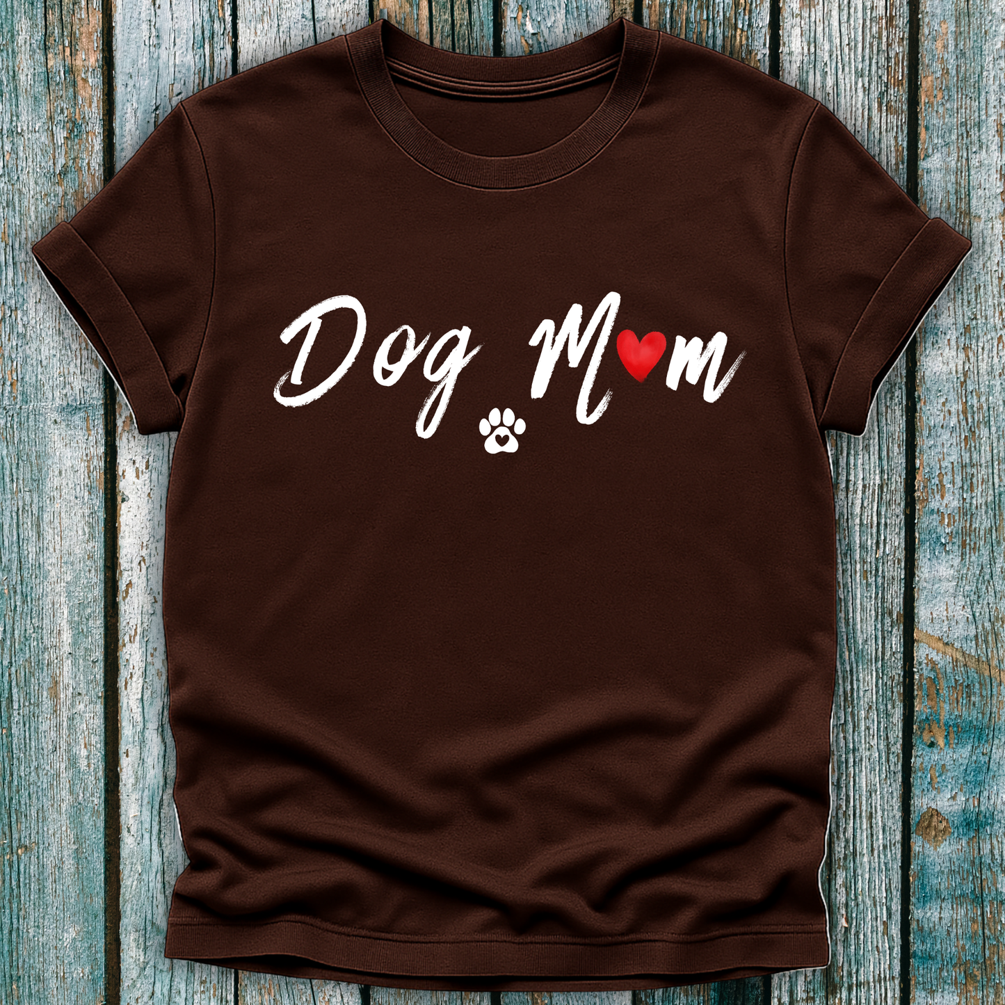 Brown t-shirt with 'Dog Mom' 'Dog Mum' text and heart and paw graphic on a wooden surface