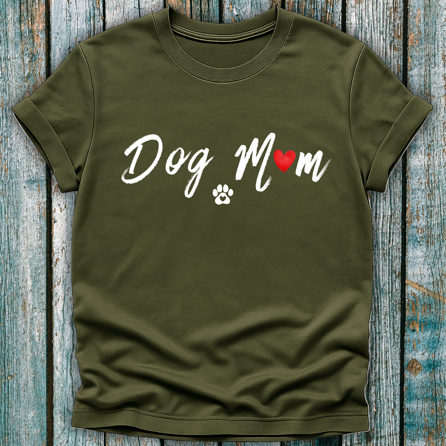 Green t-shirt with 'Dog Mom' 'Dog Mum' text and heart and paw graphic on a wooden surface