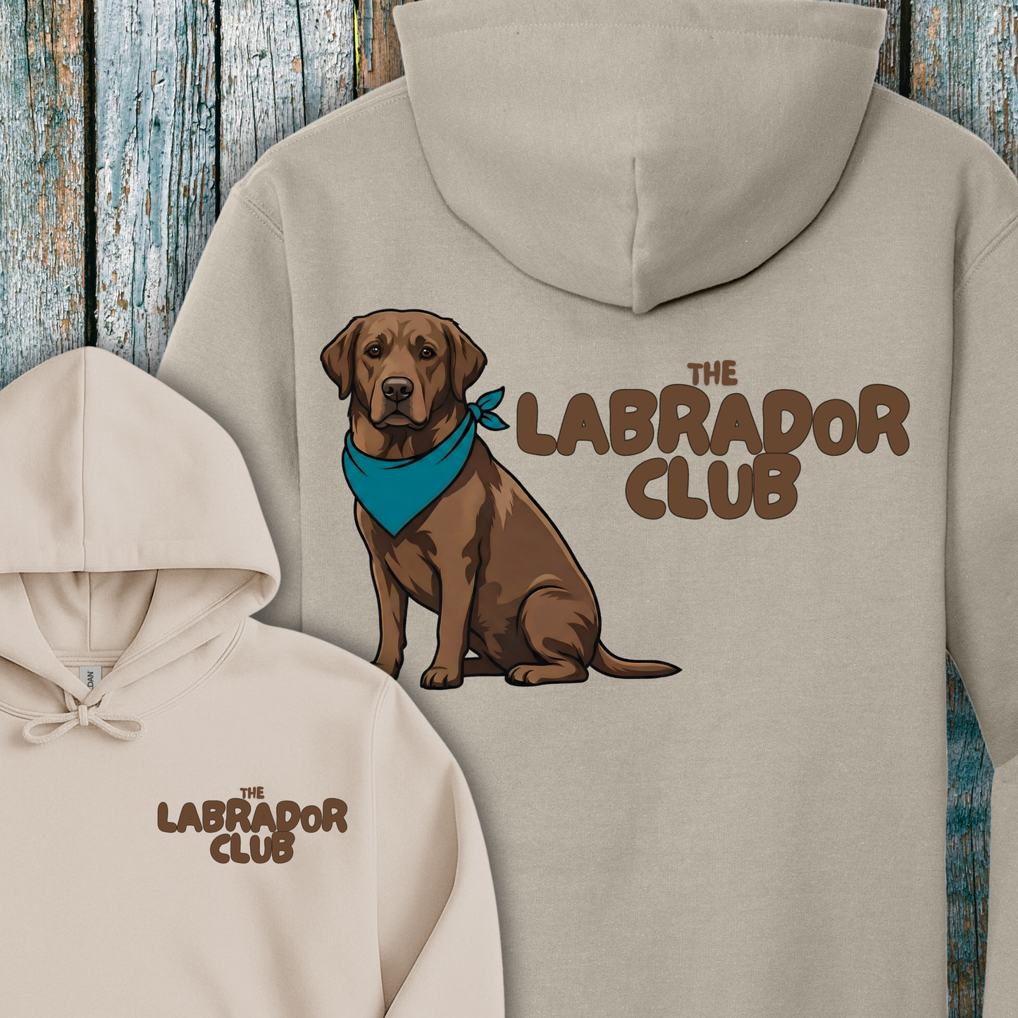 Beige hoodie with a chocolate labrador dog illustration and 'The Labrador Club' text on a wooden background