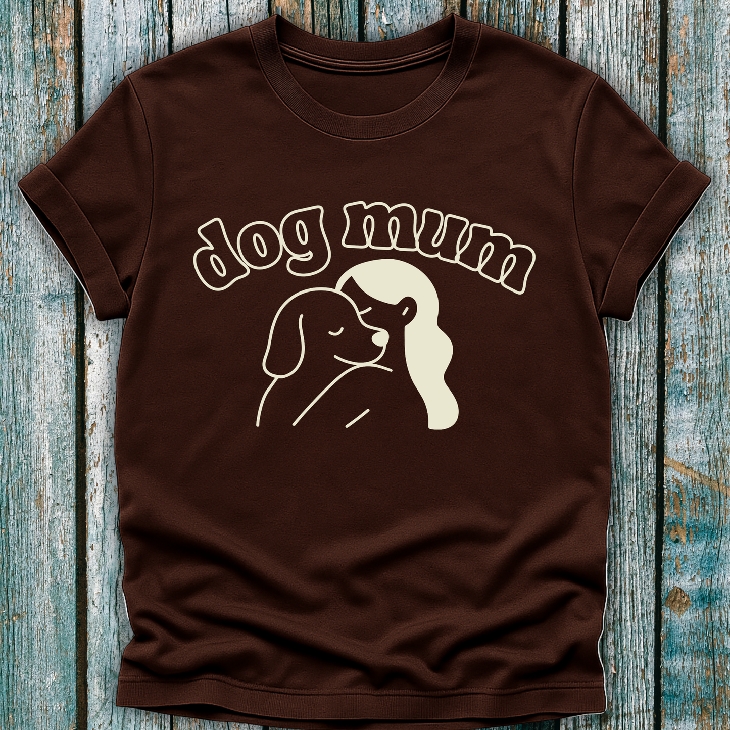 Brown t-shirt with 'dog mum' text and dog illustration on a wooden surface