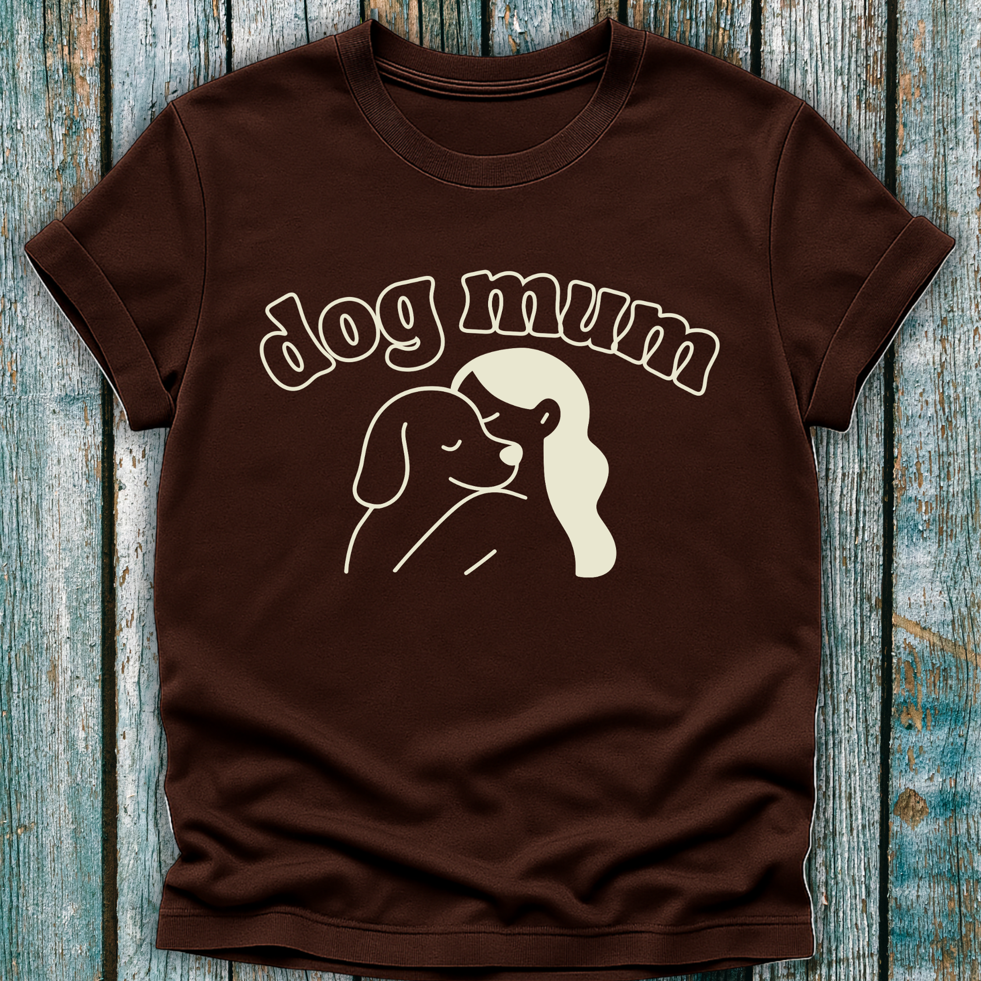 Brown t-shirt with 'dog mum' text and dog illustration on a wooden surface