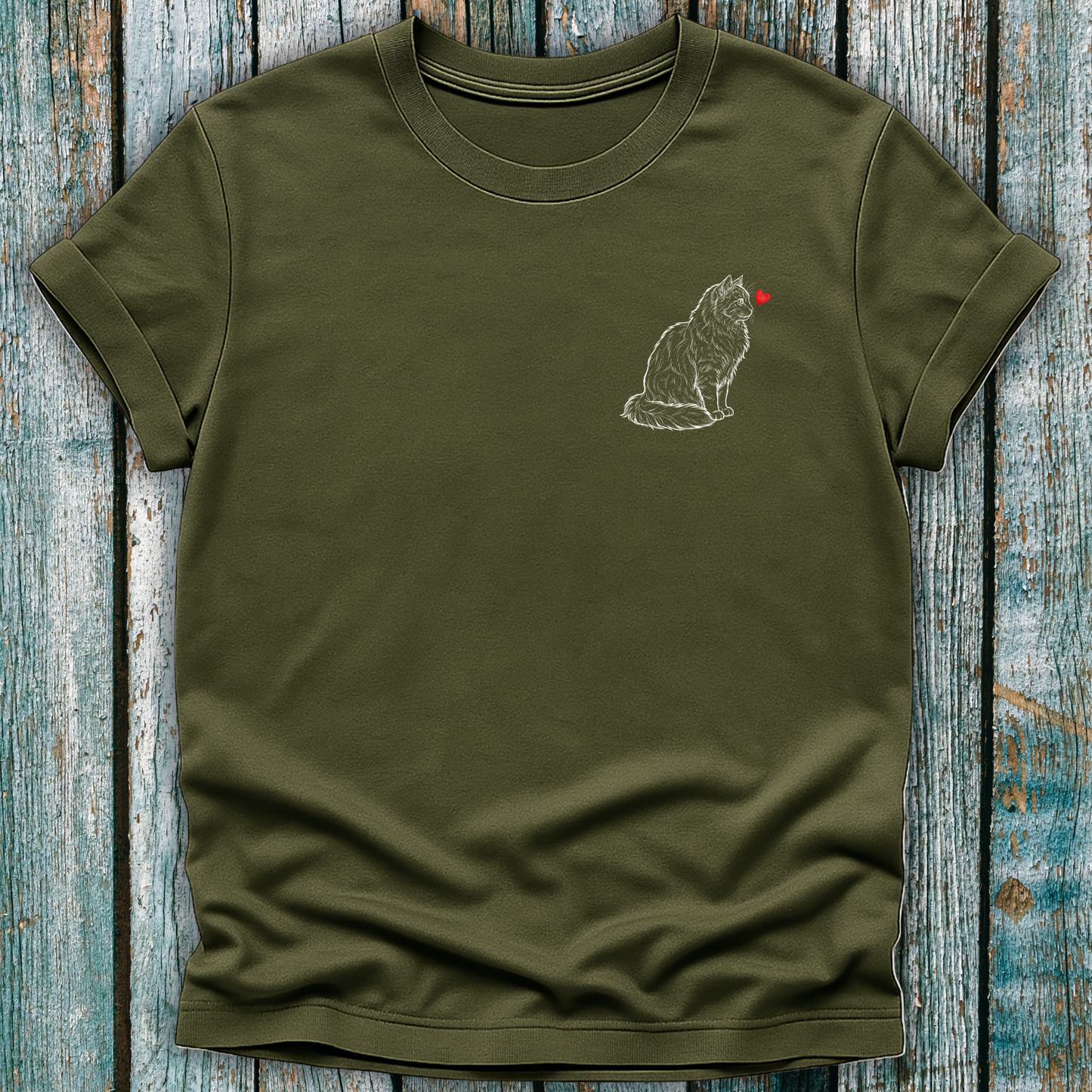 Green t-shirt with a cat graphic and red heart on a wooden surface