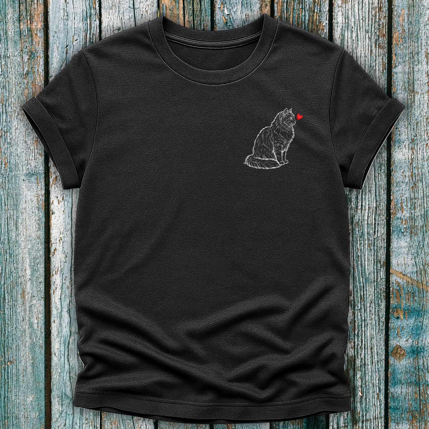 Black t-shirt with a cat graphic and red heart on a wooden surface