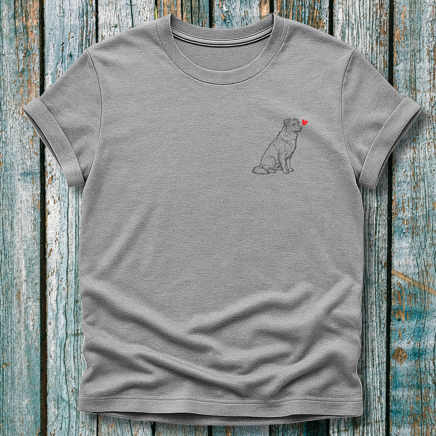 Gray  t-shirt with a Greyhound dog graphic and a red heart on a wooden surface