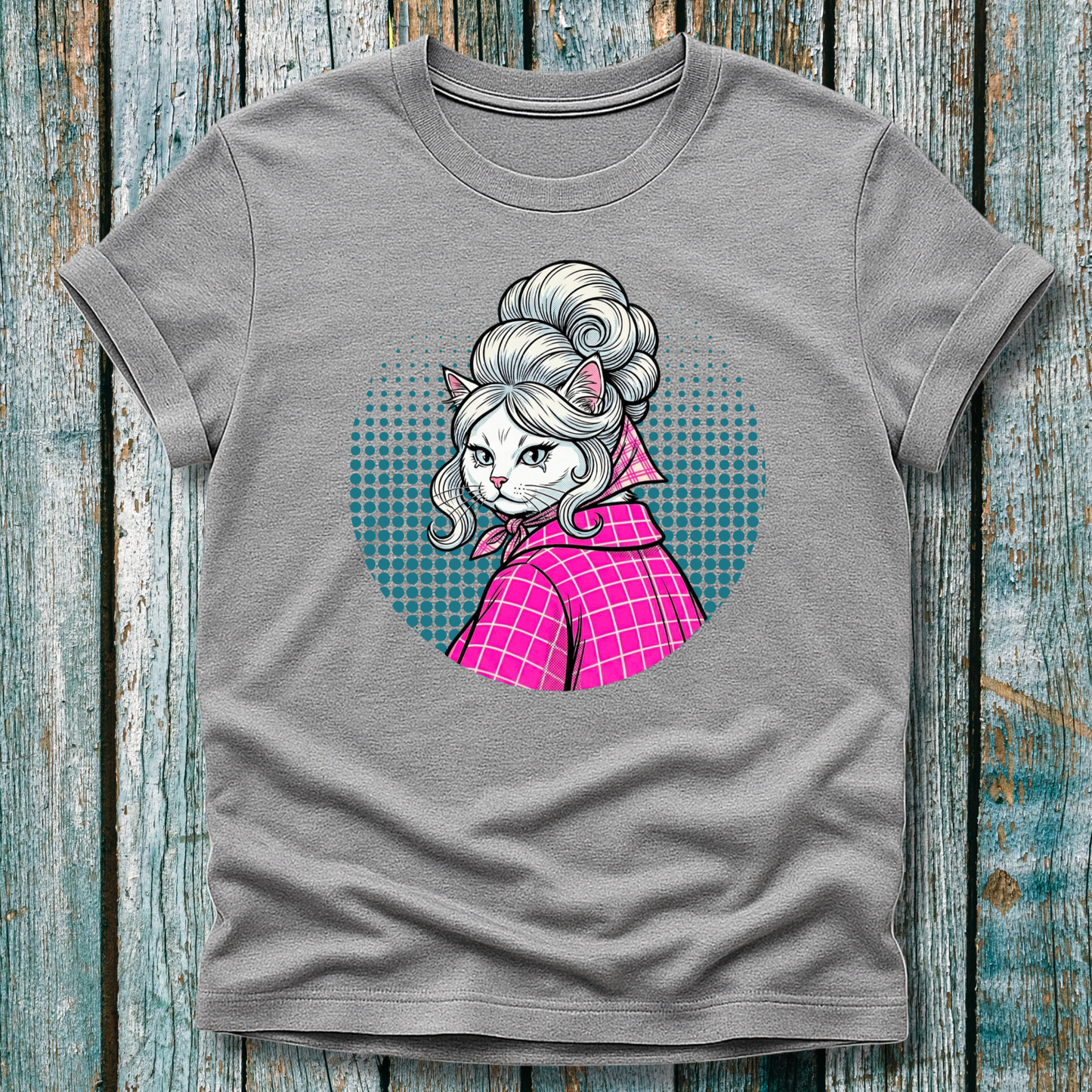 Gray  t-shirt with a colorful graphic of a pop art cat character in a pink outfit on a wooden surface