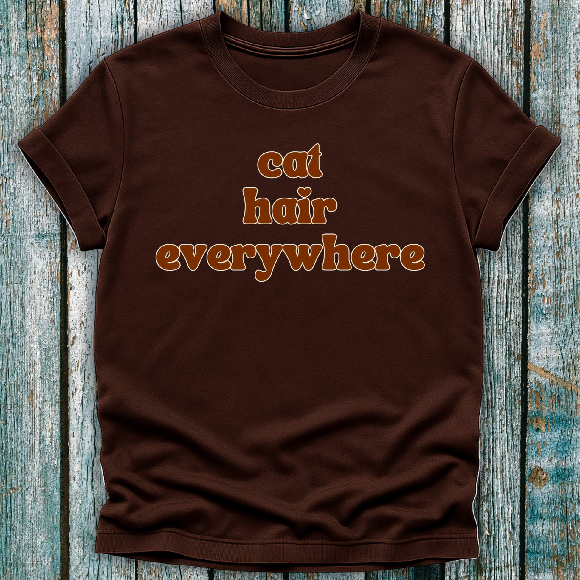 Brown t-shirt with 'cat hair everywhere' text on a wooden surface