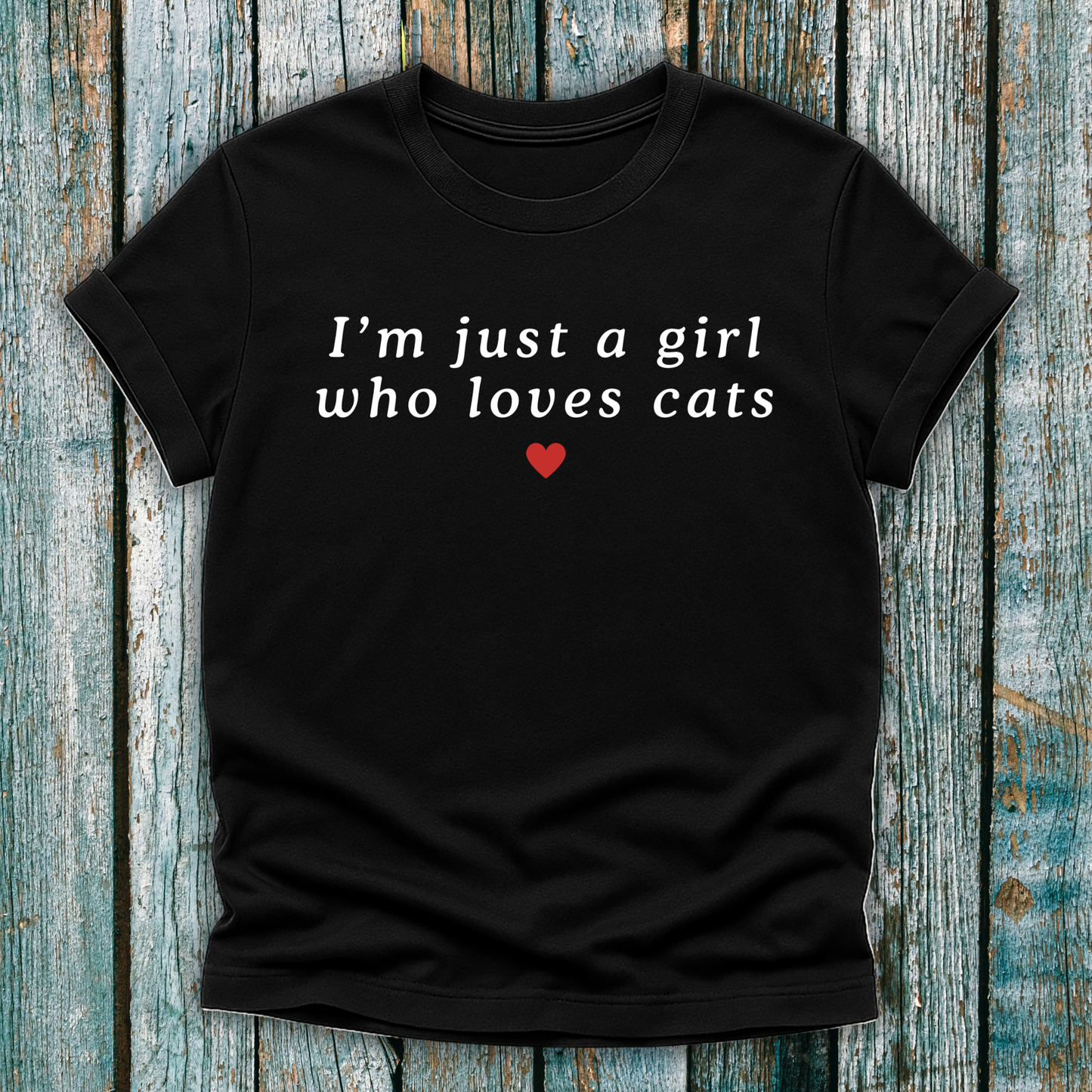 Black t-shirt with 'I'm just a girl who loves cats' text on a wooden surface