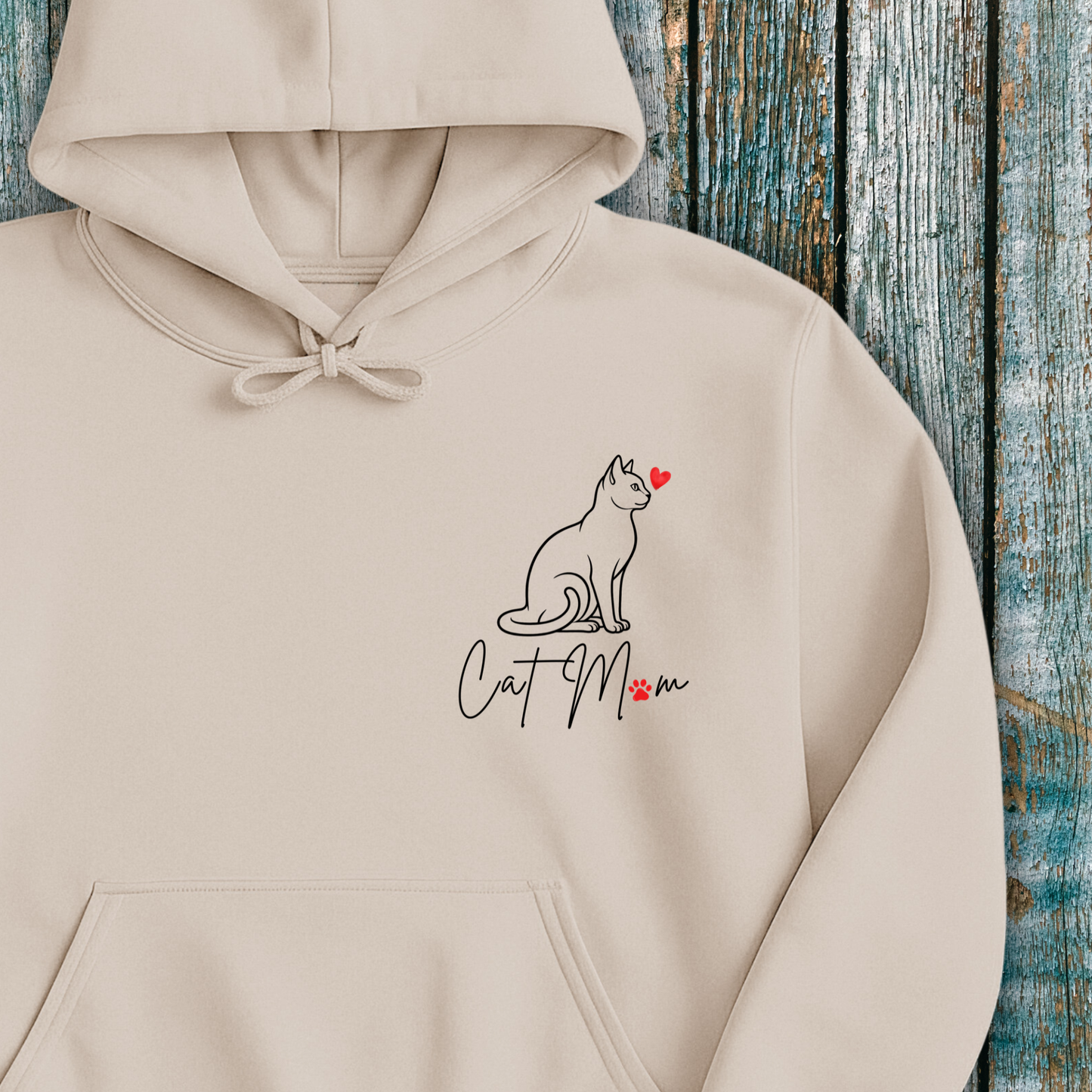 Beige hoodie with 'Cat Mom' graphic and red heart on a wooden background