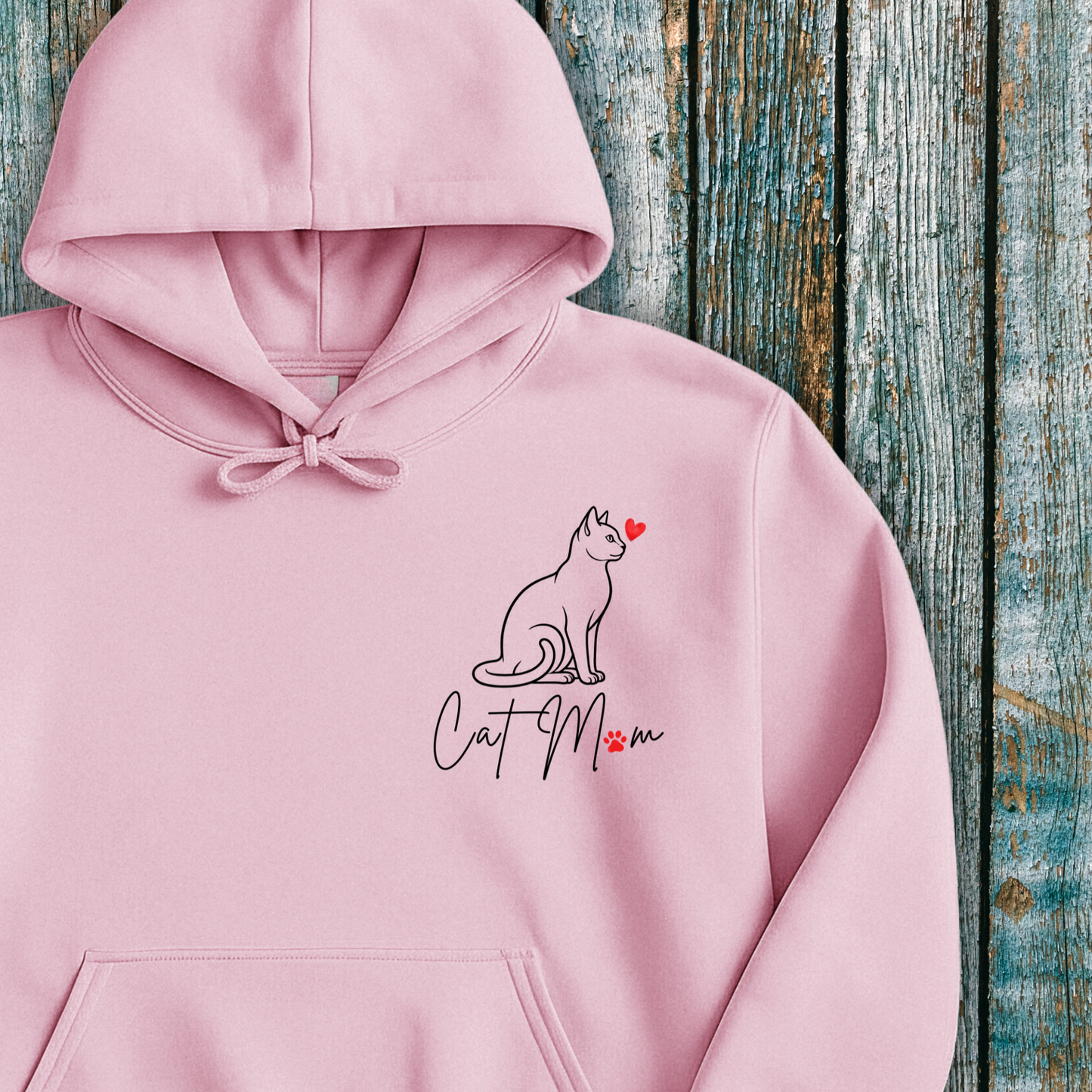 Pink hoodie with 'Cat Mom' graphic and red heart on a wooden background