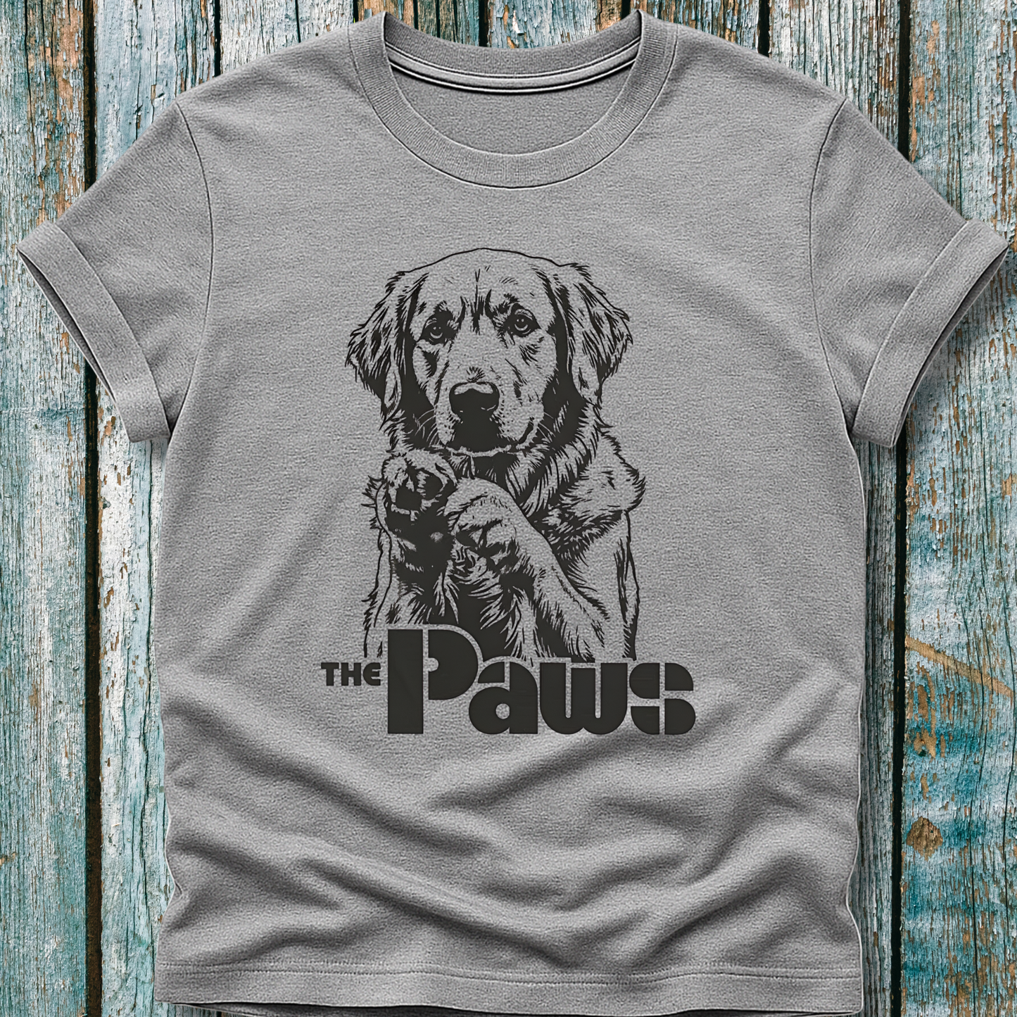 Gray t-shirt with a dog graphic and 'The Paws' text on a wooden surface