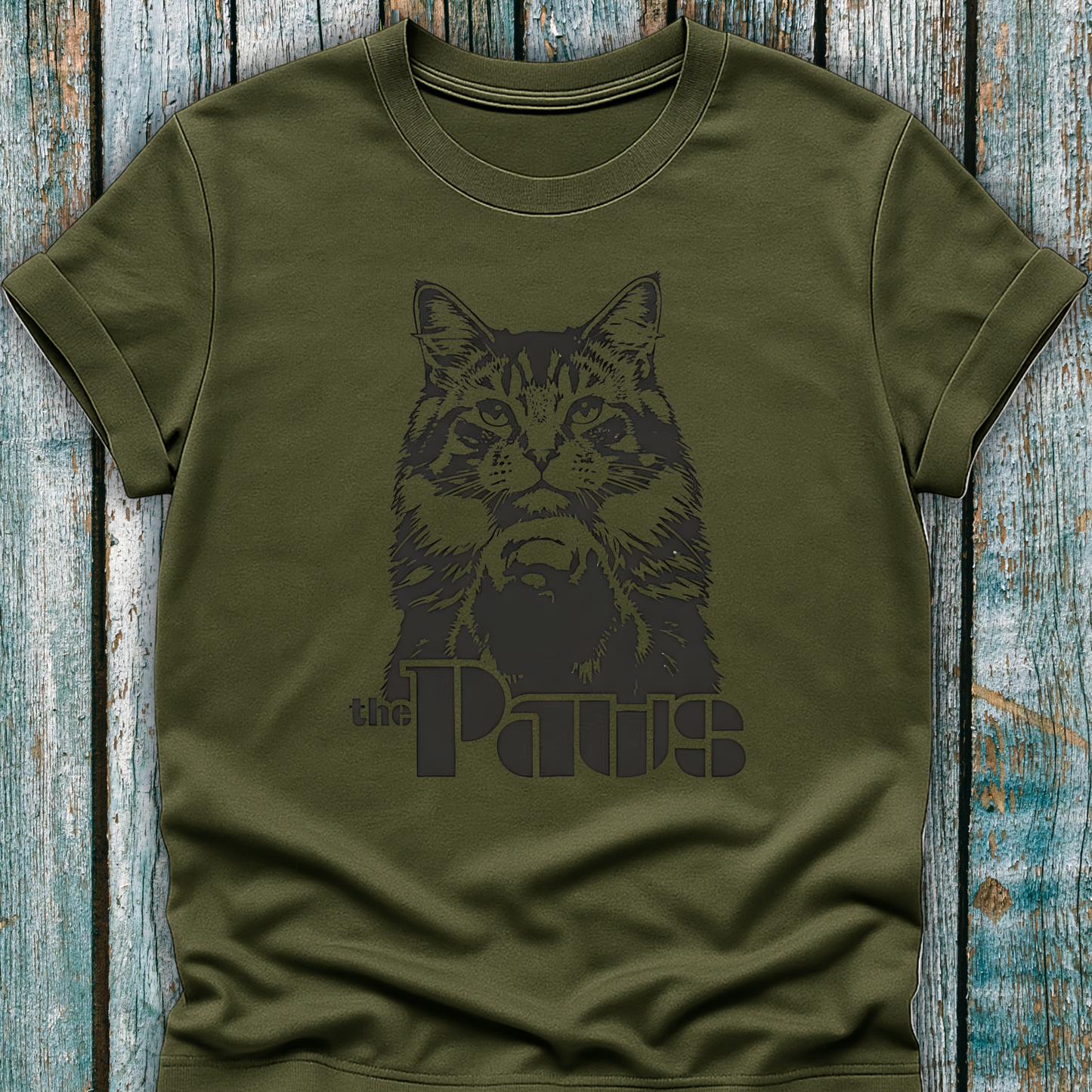 Green t-shirt with a black cat graphic and 'the Paws' text on a wooden surface