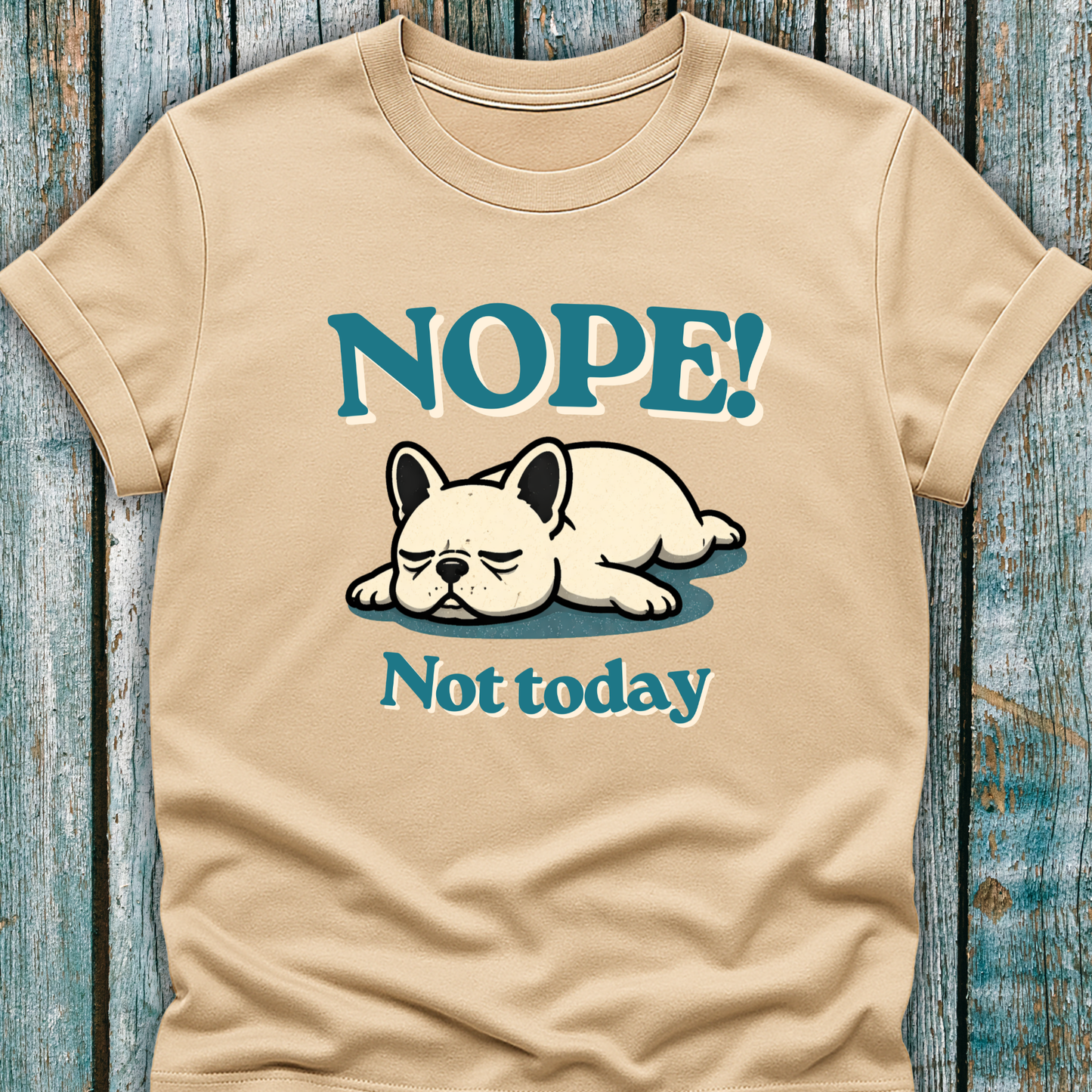 Beige t-shirt with a cartoon dog and text 'NOPE! Not today' on a wooden surface