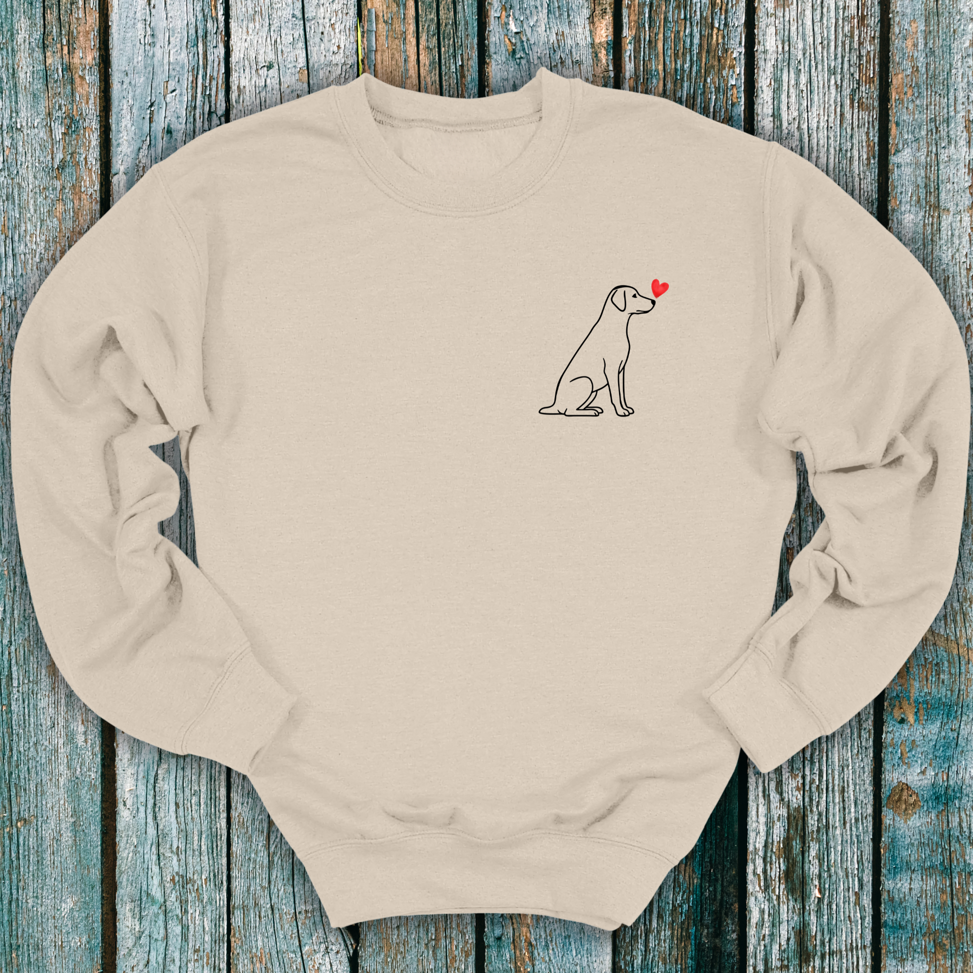 Beige sweatshirt with a Labrador dog and heart design on a wooden surface