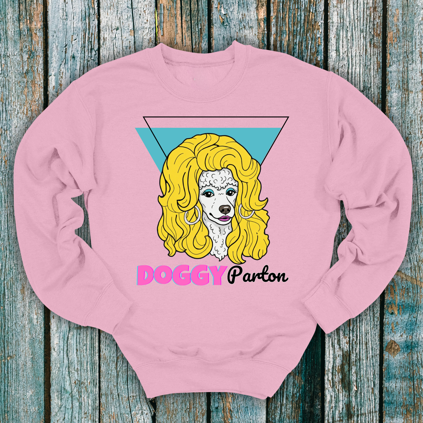 Pink sweatshirt with a graphic of a poodle dog and Doggy Parton text on a wooden background