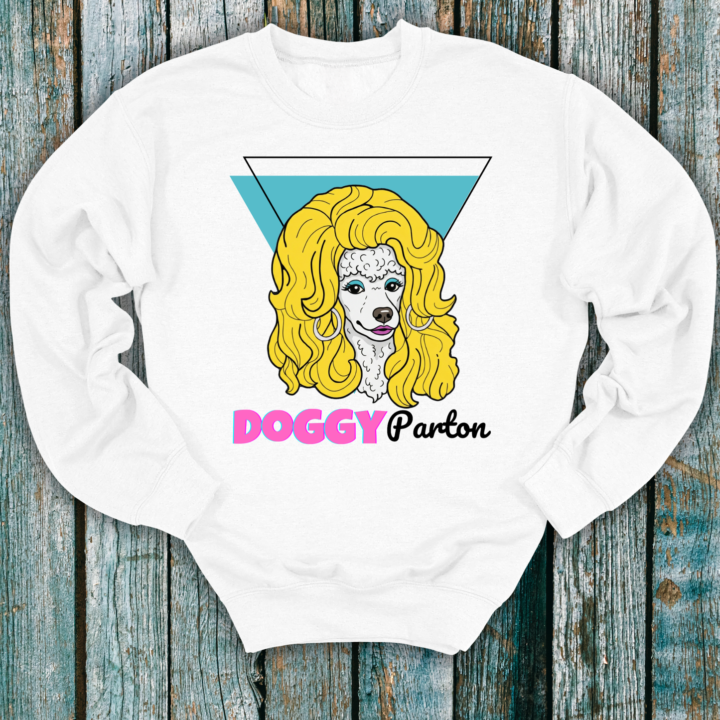White sweatshirt with a graphic of a dog with blonde hair and 'Doggy Parton' text on a wooden background